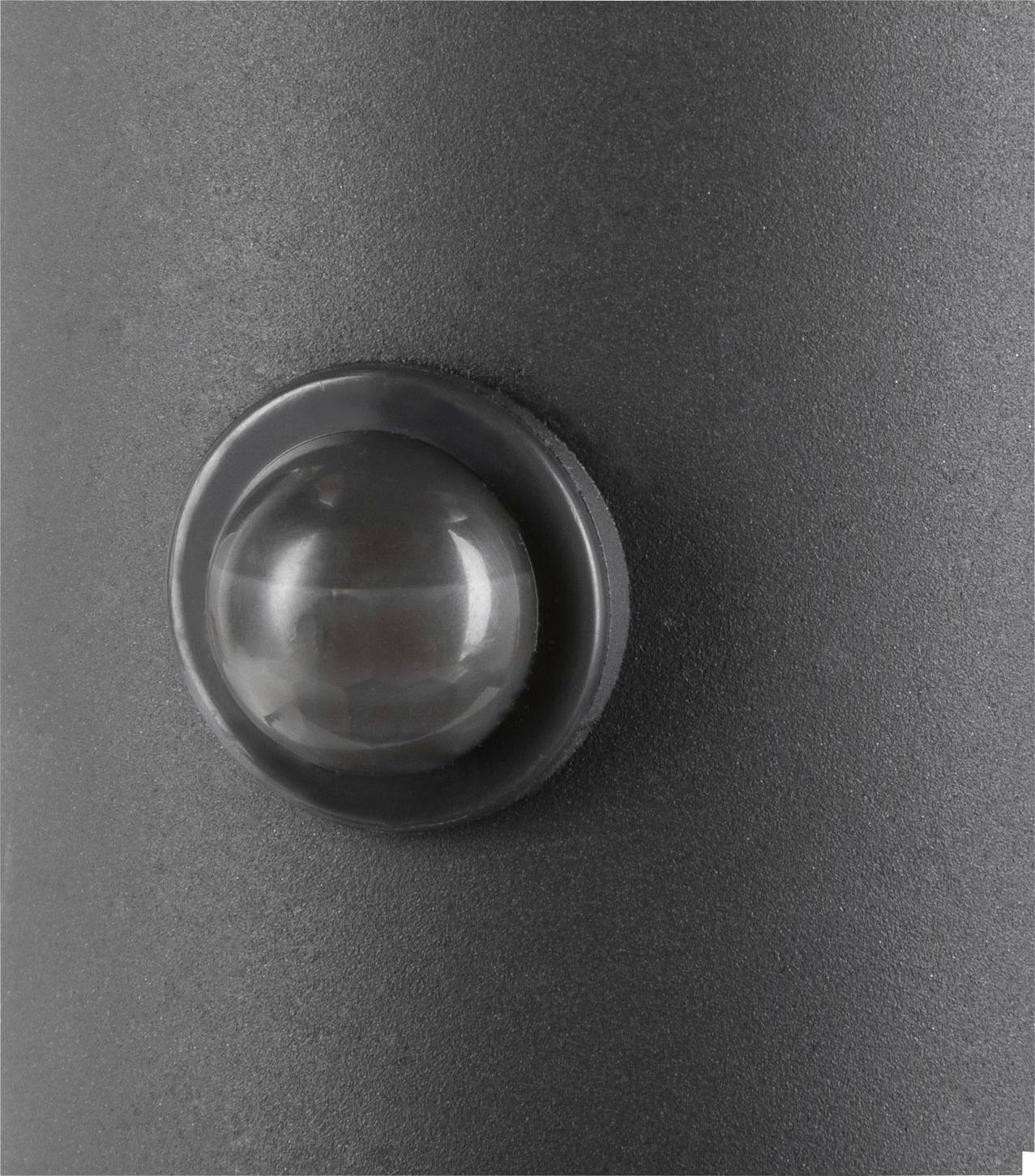 Close-up van een bewegingssensor op een grijze ondergrond. De sensor is rond en licht verhoogd.