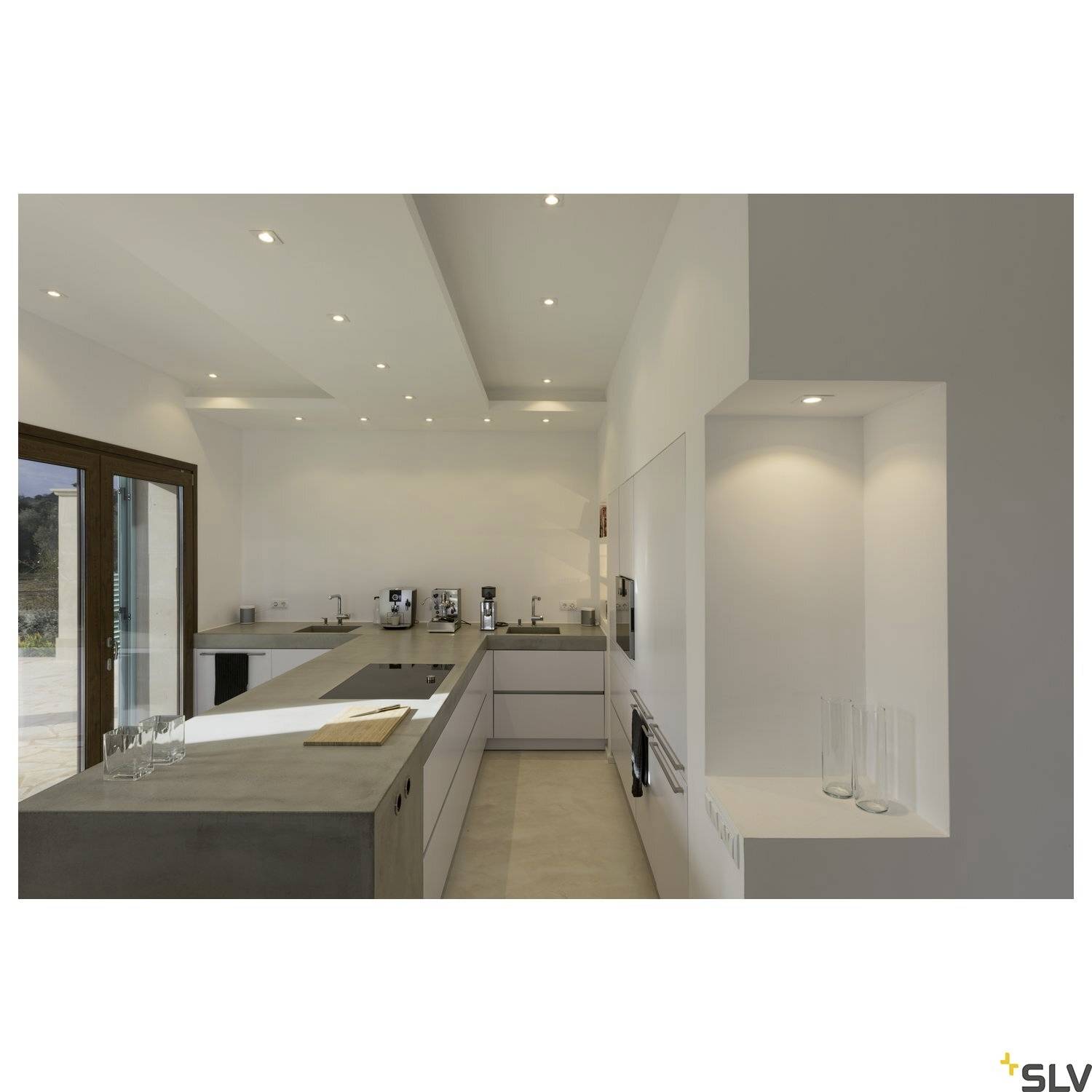 Moderne keuken met betonnen werkblad; ingebouwde oven, meerdere koffiemachines, ramen met natuurlijk licht. Minimalistisch design.