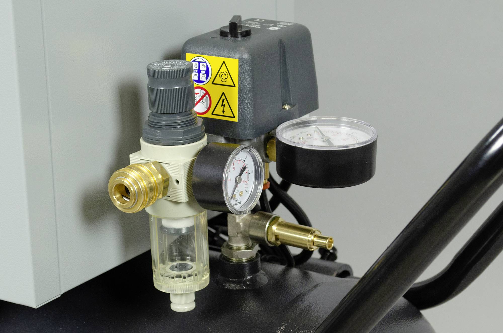 Manometer en drukregelaar op een luchtcompressor, display toont de huidige druk. Belangrijke waarschuwingen op het apparaat.