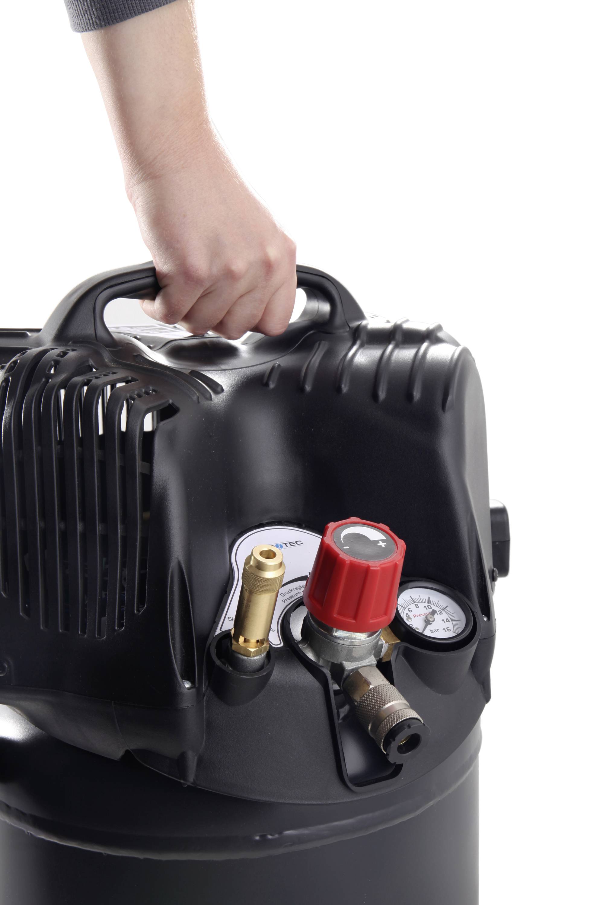 Een hand houdt de handgreep vast van een zwarte luchtcompressor met een rood ventiel en drukmeter op een witte achtergrond.