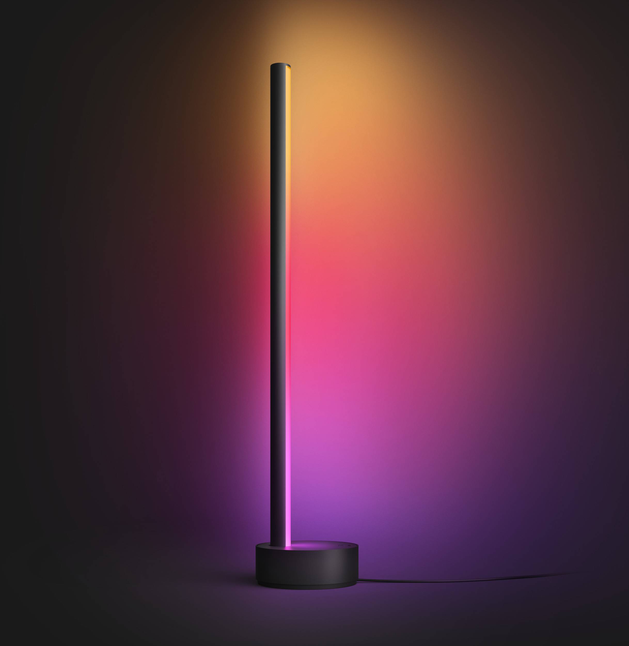 Een slanke, staande lamp op een rond voetstuk straalt levendige kleuren van roze tot oranje uit en creëert een sfeervolle omgeving.
