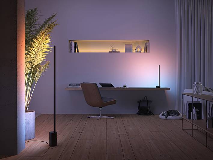 Gezellige kamer met een modern bureau, een boek op tafel, een stijlvolle lamp, een fauteuil en een slapende kat op de vloer, met rustgevende verlichting.