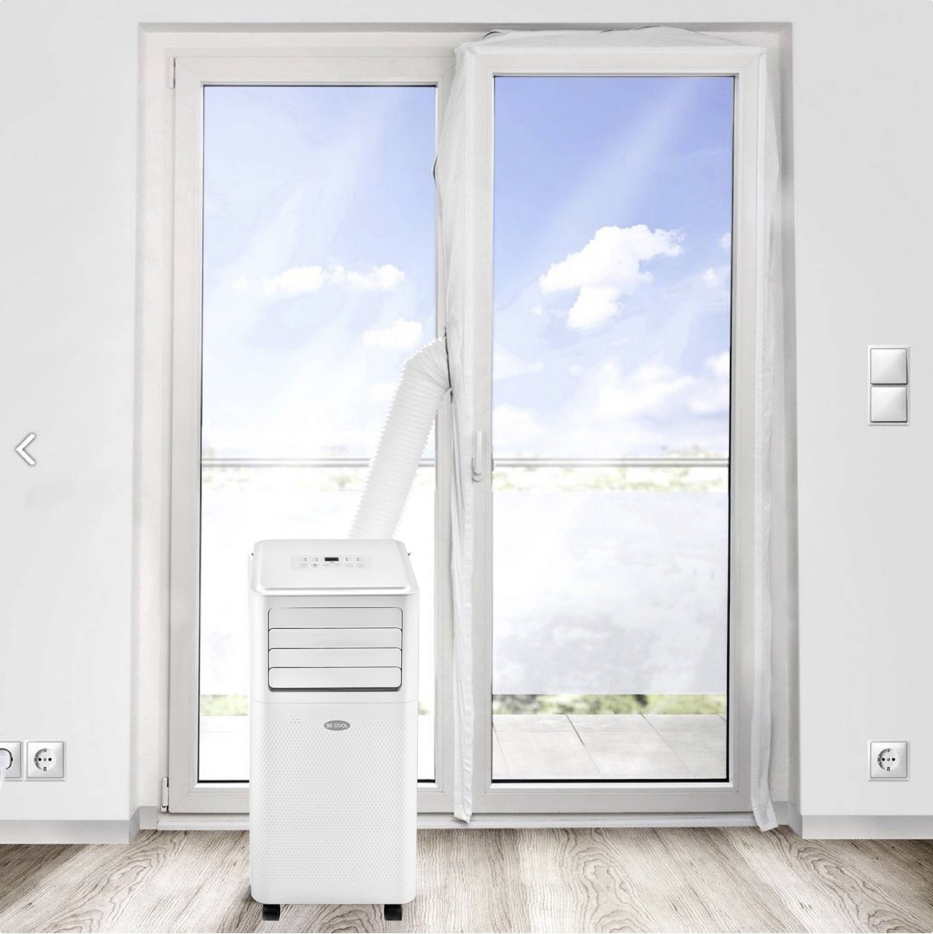Een mobiele airconditioning staat voor een openstaande terrasdeur, waarbij een afvoerslang naar buiten loopt; lichte ruimte op de achtergrond.