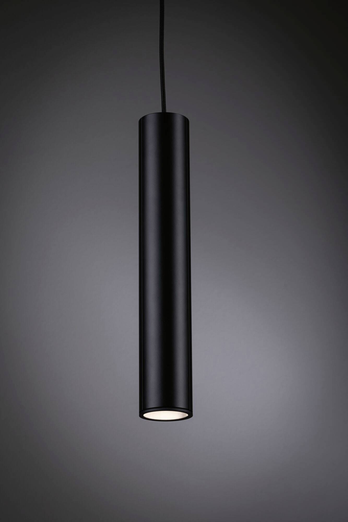Een minimalistische, cilindrische hanglamp in het zwart hangt van het plafond en schijnt naar beneden.
