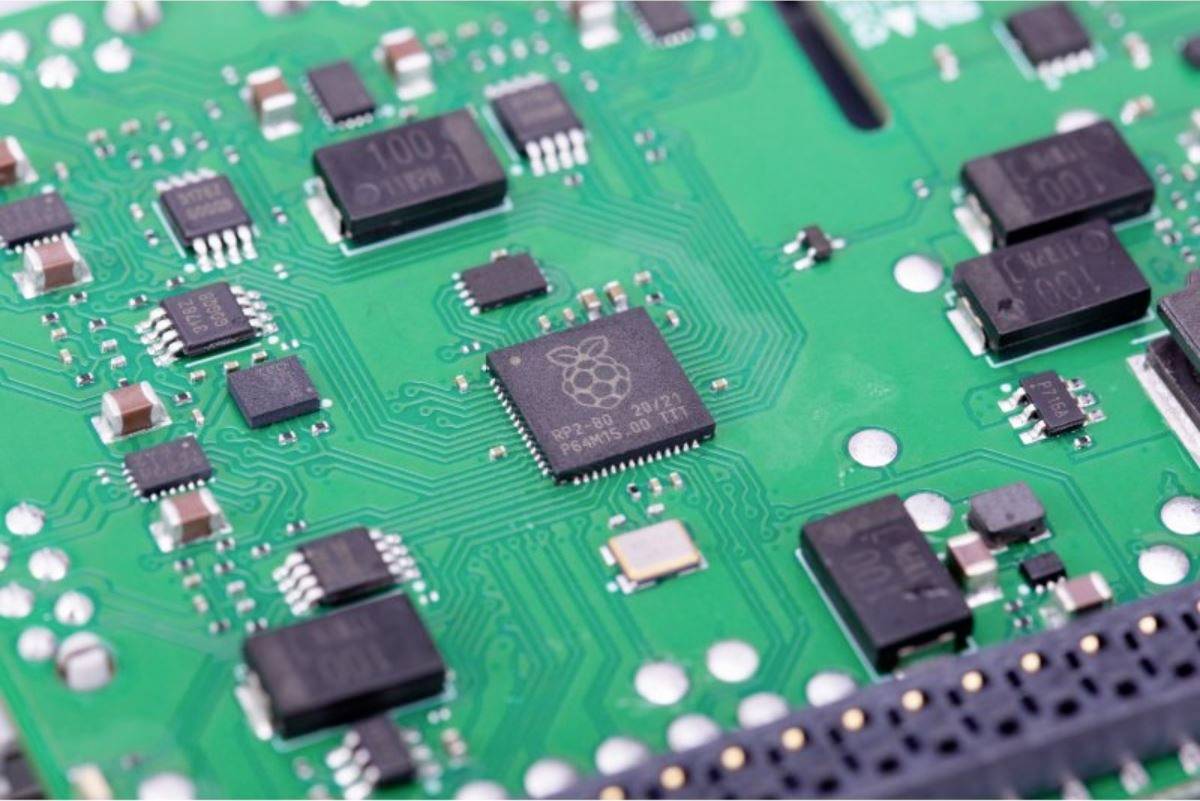 Een groene printplaat met verschillende zwarte microchips en elektronische componenten.