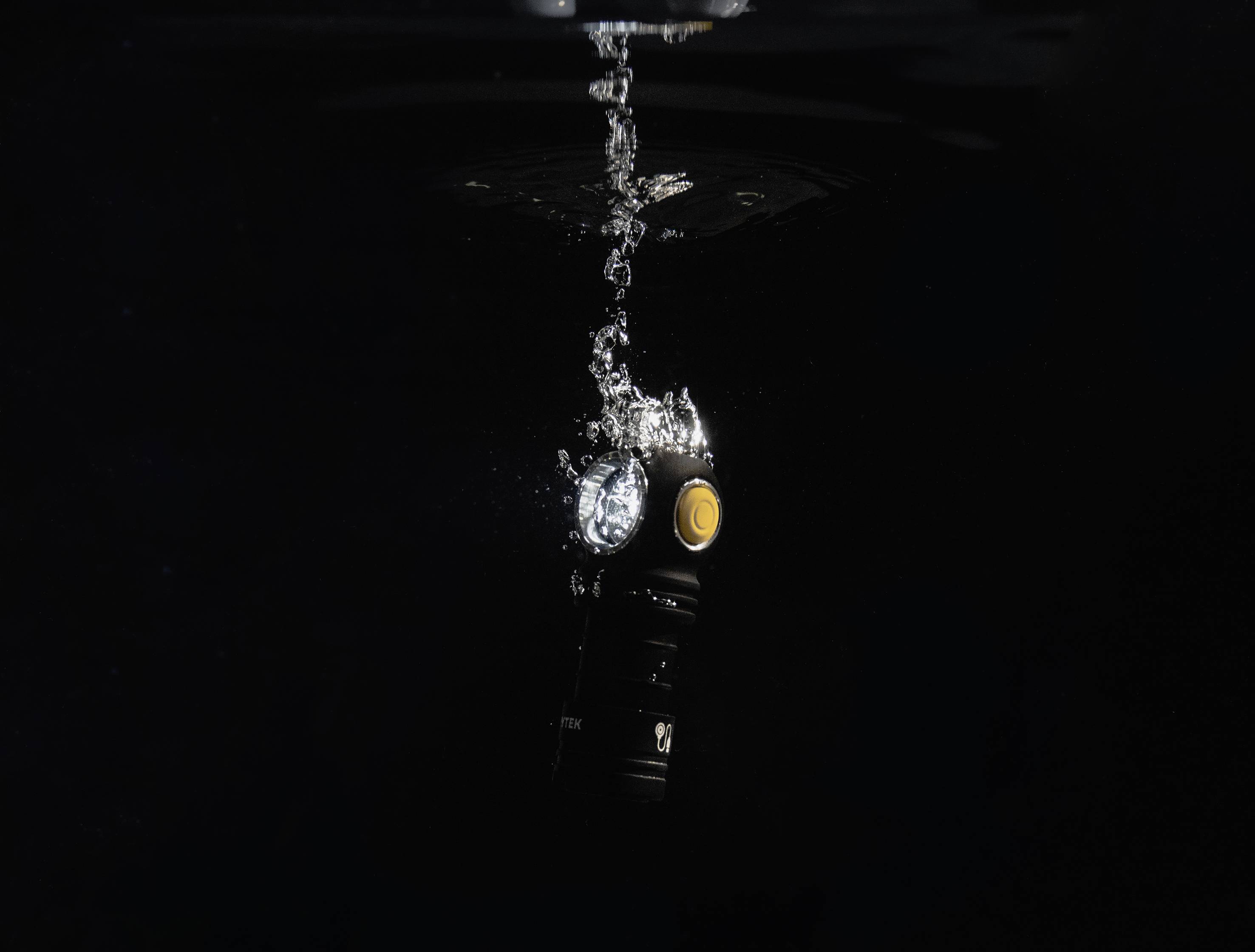 Zaklamp onder water met opstijgende bubbels; zwak licht in een donkere omgeving.