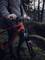 Een persoon in outdoorkleding houdt een rode mountainbike vast op een bebost pad bij schemering.