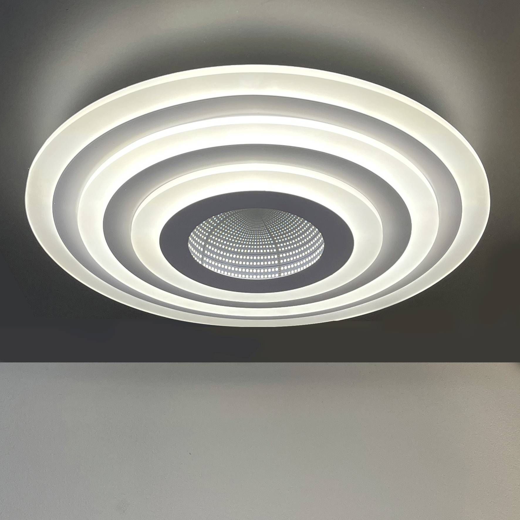 Een moderne plafondlamp met concentrische ringen die helder licht uitstralen, gemonteerd aan het plafond van een kamer.