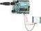 Arduino Uno-bord verbonden met een bewegingssensor via kabels. LED's, USB-poort en sensor zichtbaar. Elektronisch projectopstelling.