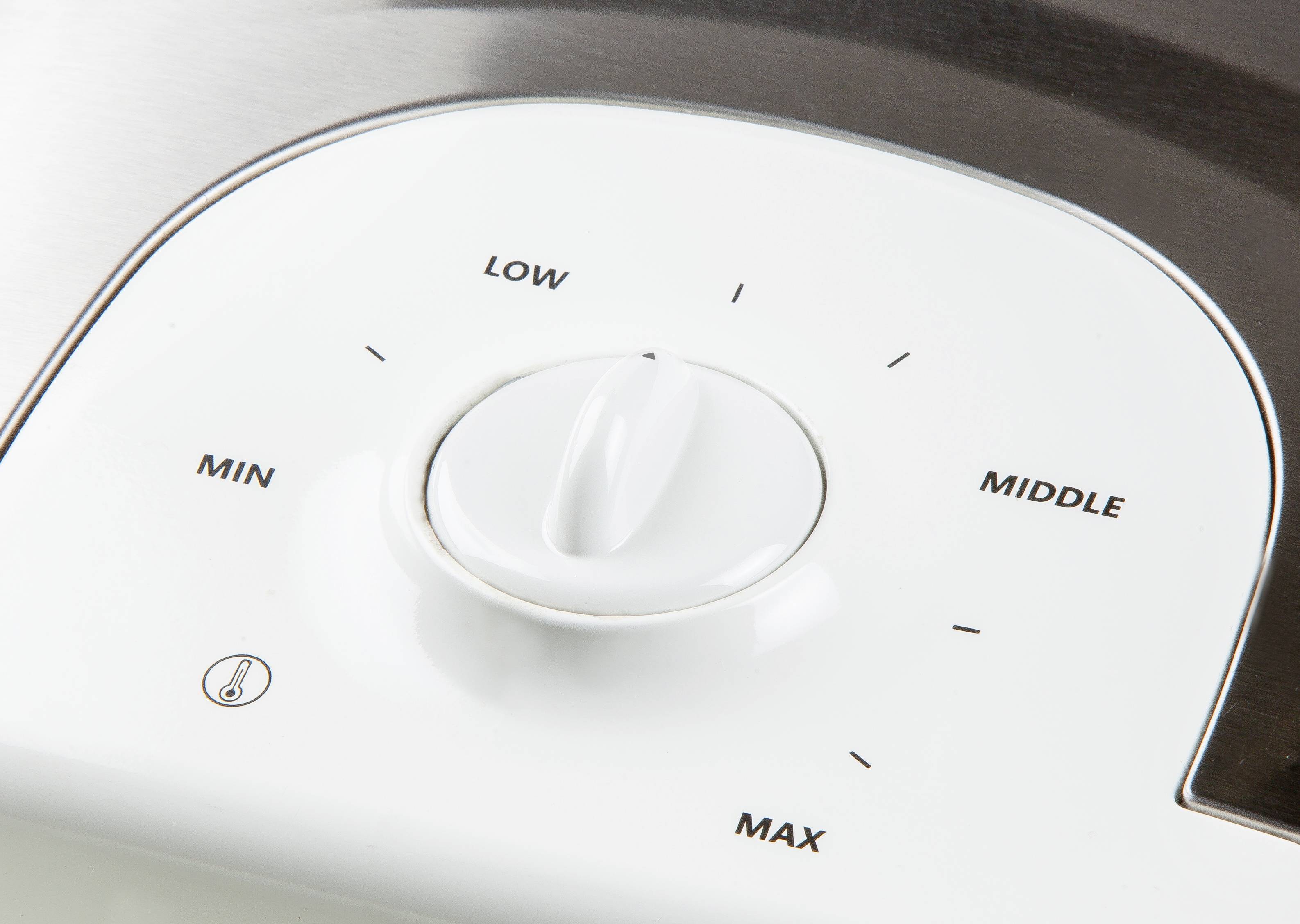 Een witte draaiknop op een apparaat, gemarkeerd met 'MIN', 'LAAG', 'MIDDEN', 'MAX'. Geeft verschillende verwarmingsniveaus aan.