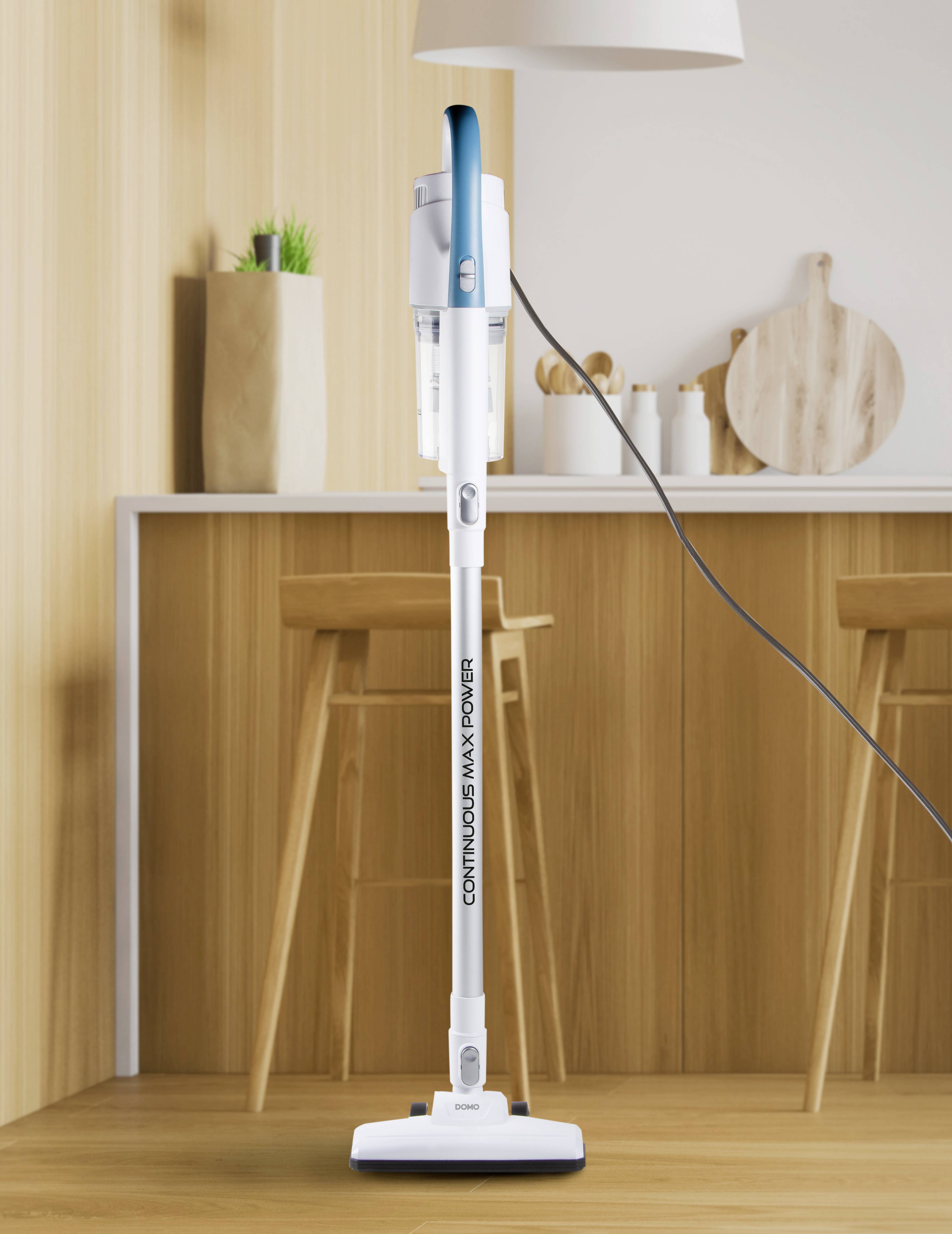 'Een witte stofzuiger met blauwe accenten staat in een moderne keuken voor een bar met barkrukken en houten decoraties.'