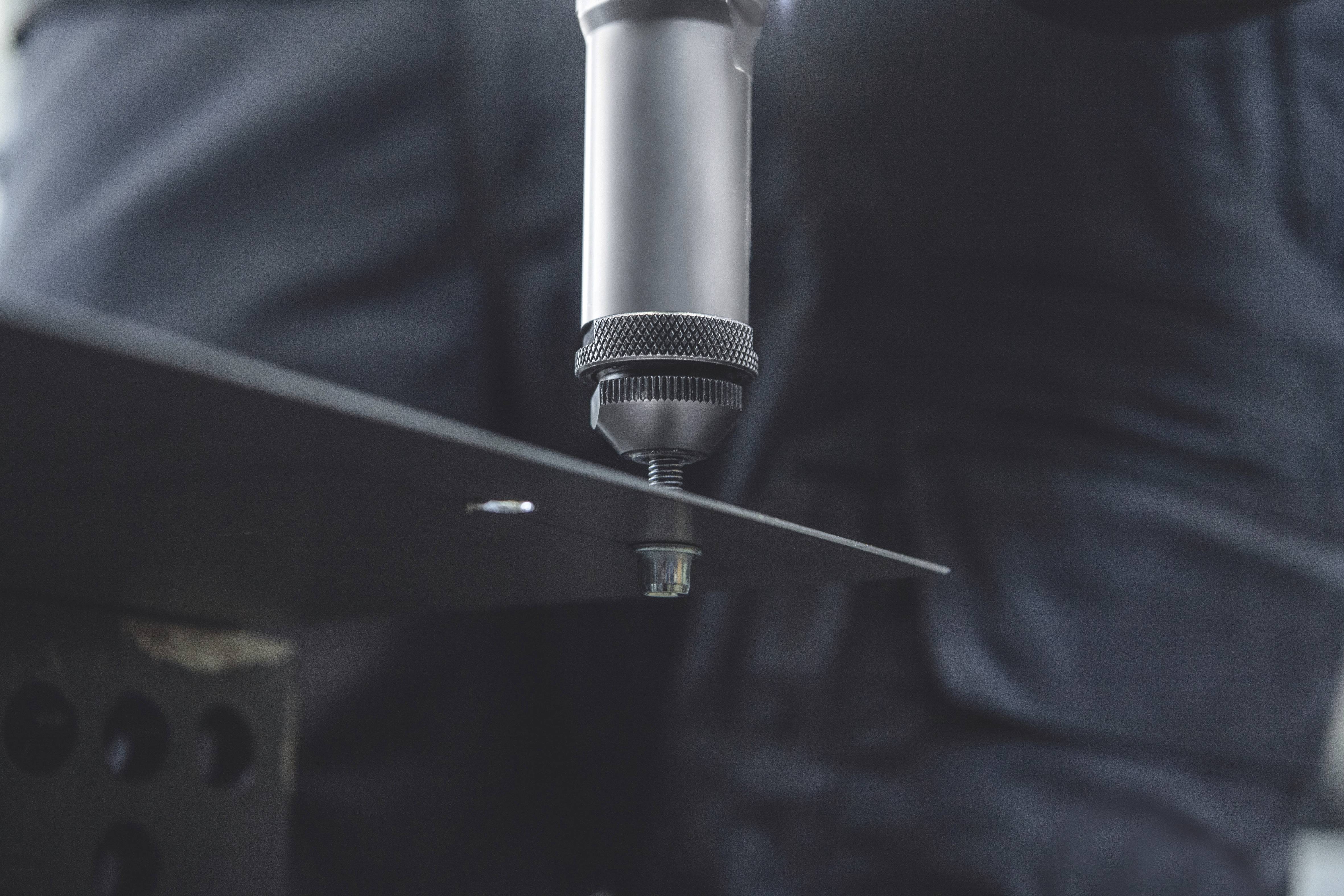 Close-upfoto van een gereedschap dat een schroef in een metalen plaat draait. De focus ligt op ambachtelijk werk en precisie.