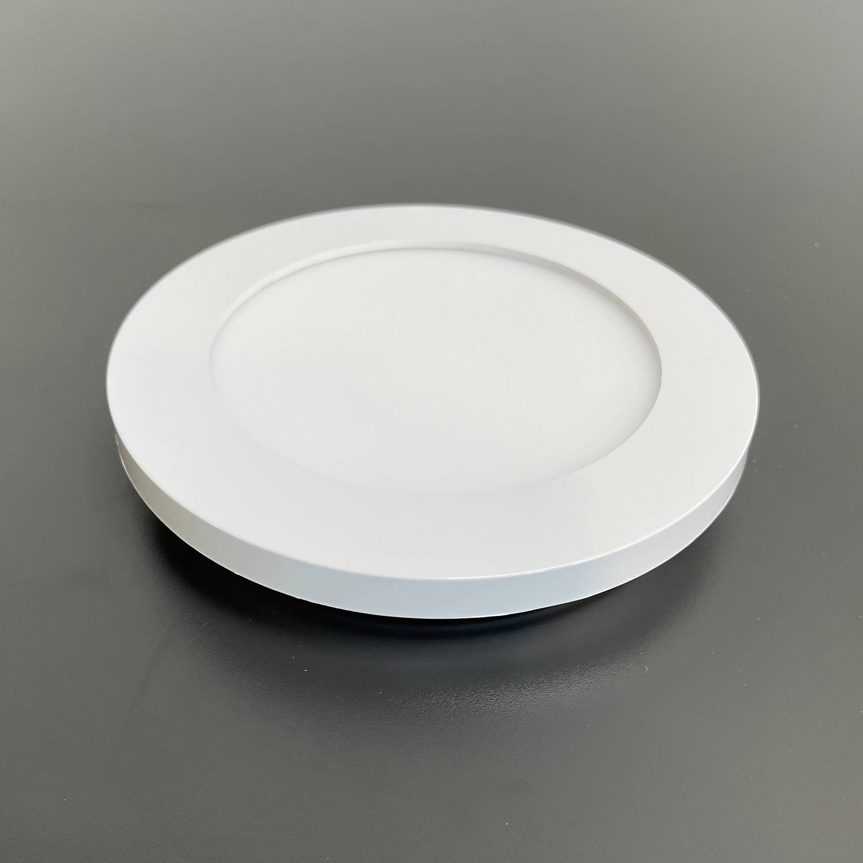 Een ronde, witte plafondlamp met een eenvoudig design op een grijze achtergrond.