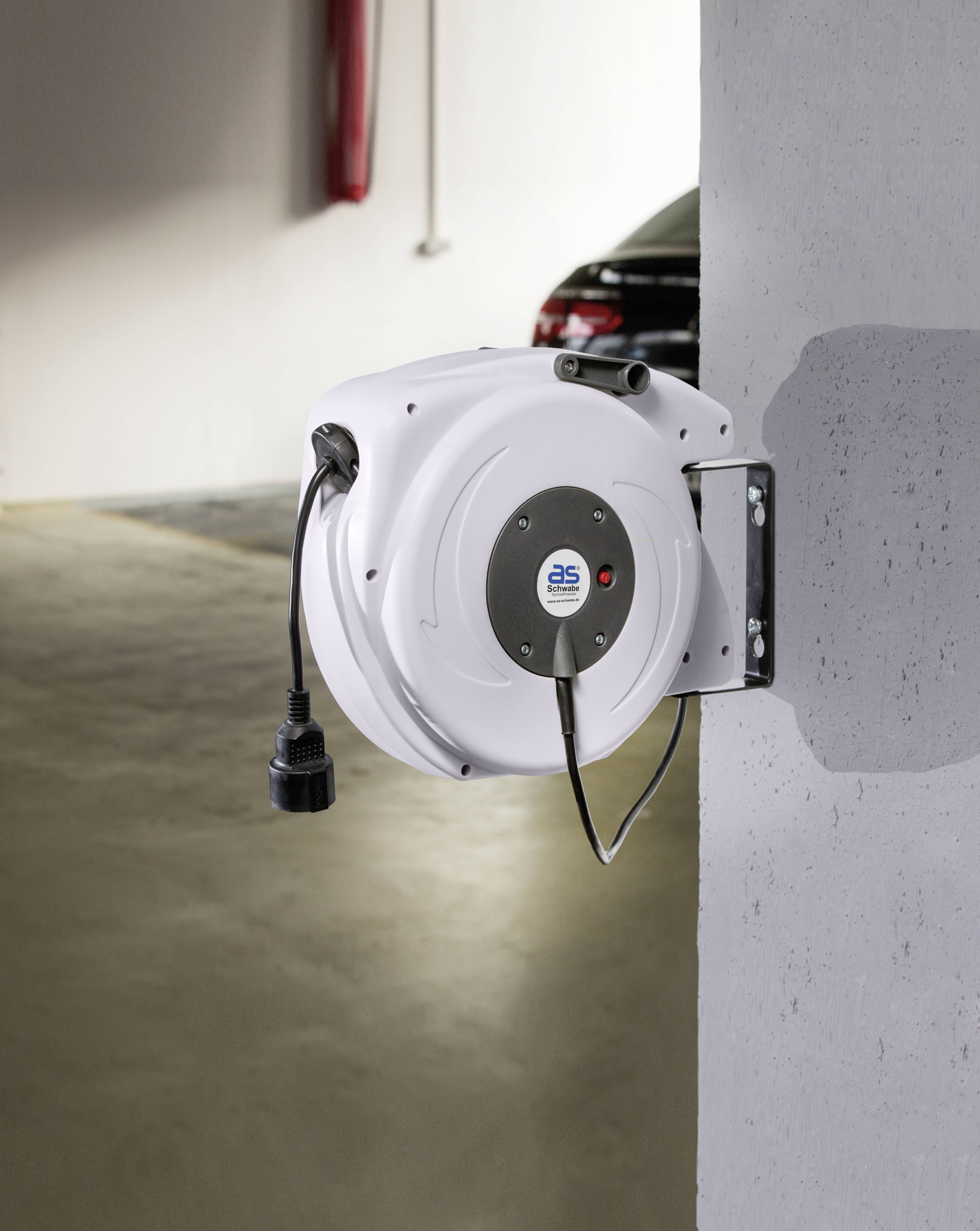 Witte kabelhaspel bevestigd aan een betonnen muur, voor een onscherpe achtergrond met een geparkeerde auto.