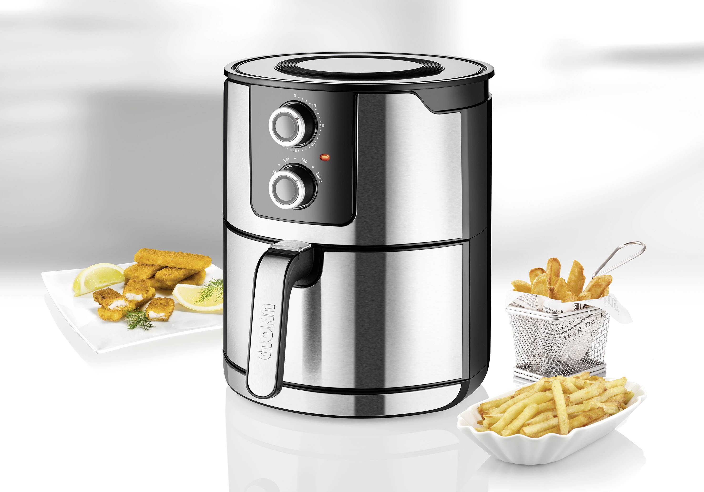 RVS airfryer met twee draaiknoppen, ingesteld op 200°C. Omringd door borden met friet en gefrituurde snacks.