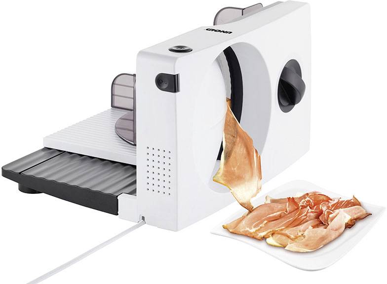 Elektrische snijmachine snijdt dunne plakjes ham op een bord. Hij is wit met een zwart instelwiel.