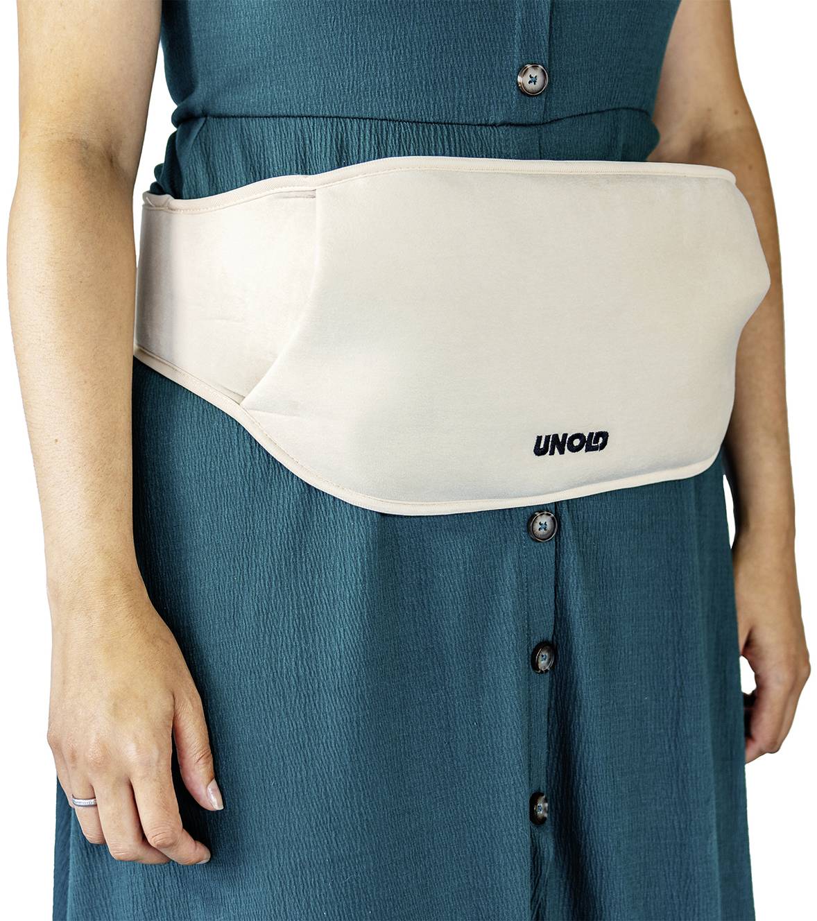Een persoon draagt een witte warmtegordel rond de taille over een turquoise jurk. Het apparaat heeft het merknaam 'UNOLD'.