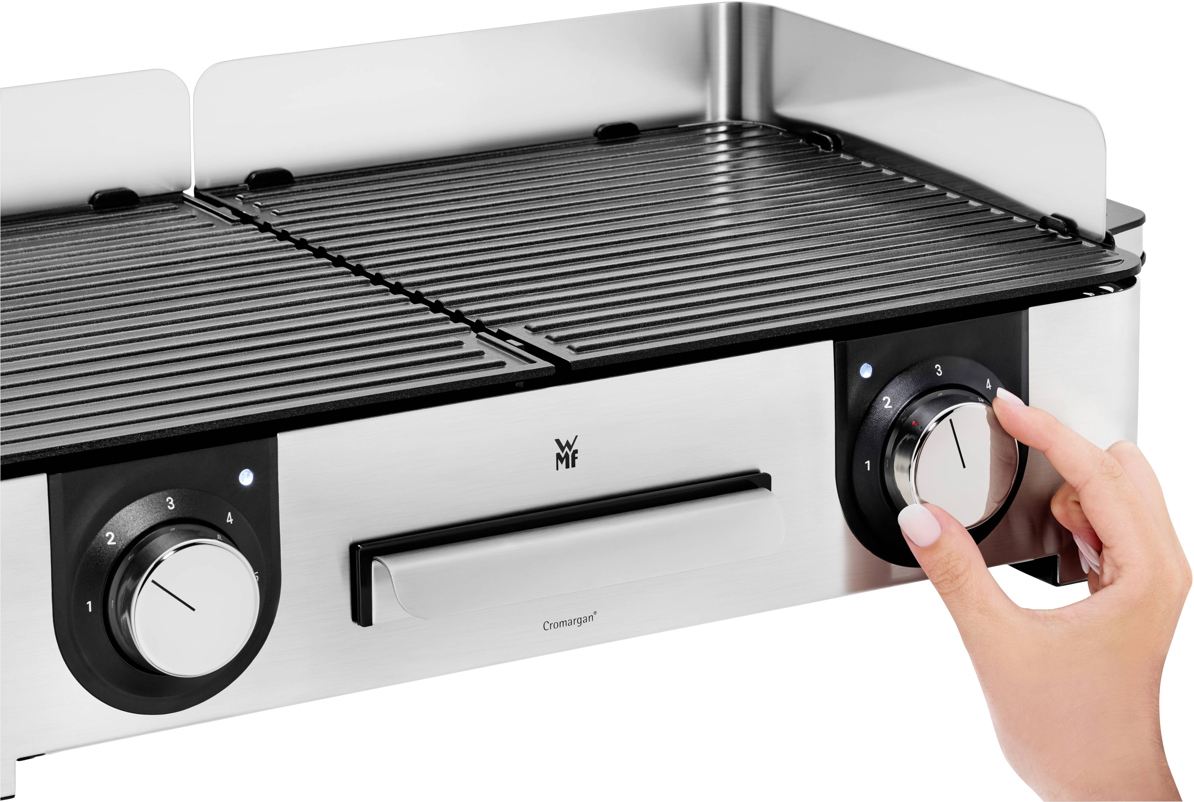 'Hand draait de instelling op een metalen grill met twee draaiknoppen en grillrooster.'