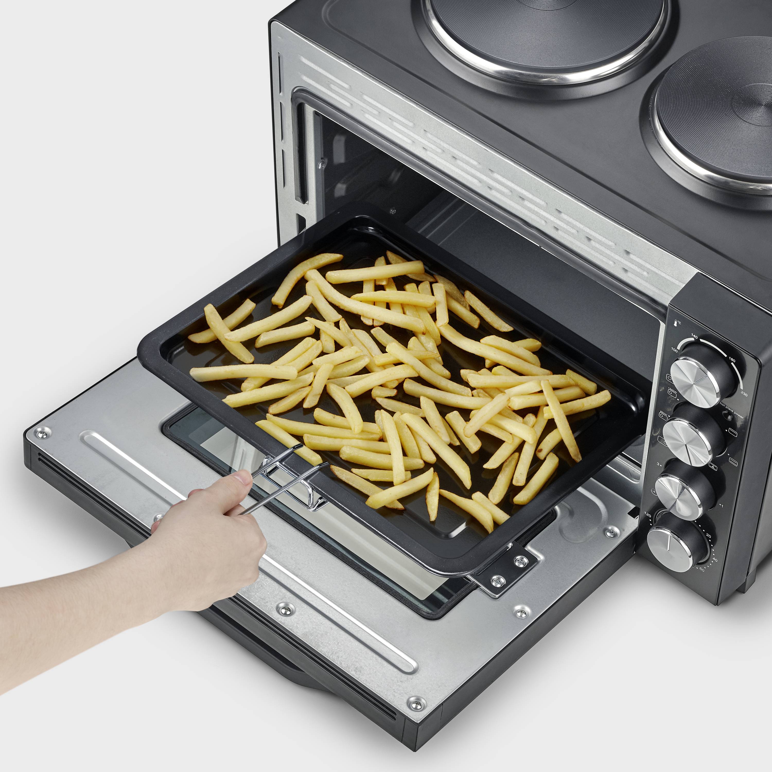 Een hand schuift een bakplaat met frietjes in een open tafeloven.