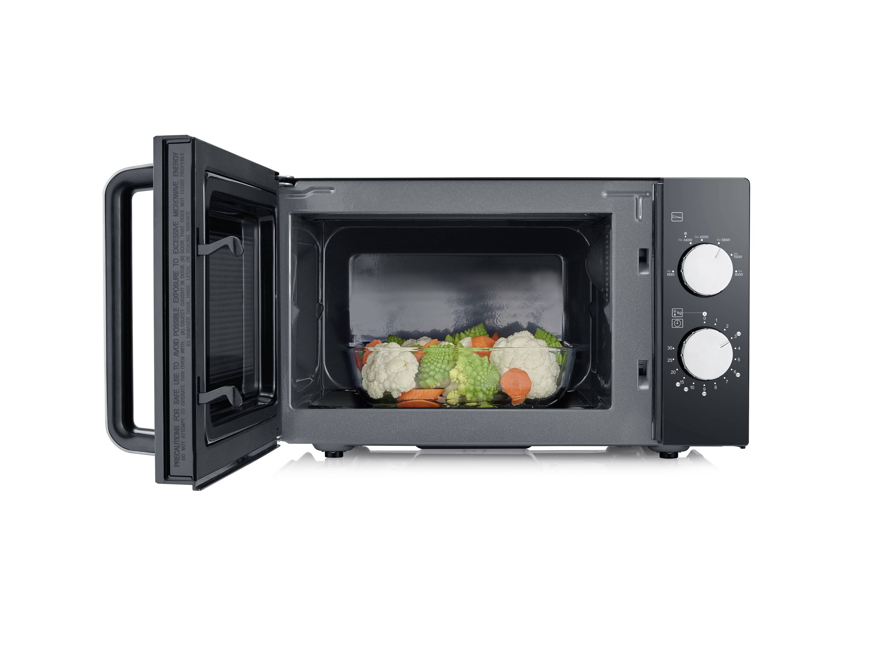 Open magnetron met een bord vol kleurrijk groenten zoals broccoli, bloemkool en wortels.