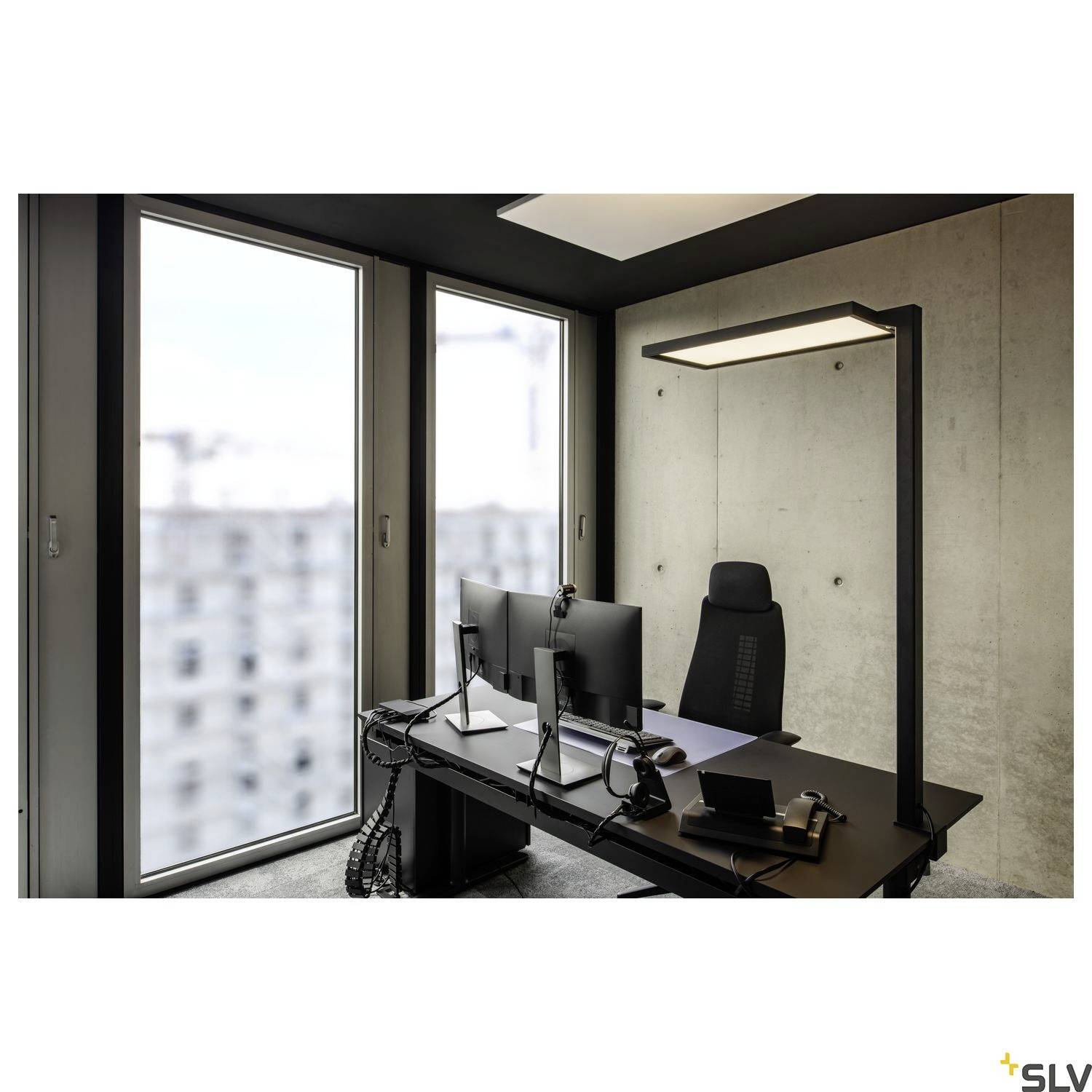 Modern kantoor met twee grote ramen, twee monitoren, toetsenbord en telefoon op een bureau. Een staande lamp verlicht de ruimte.