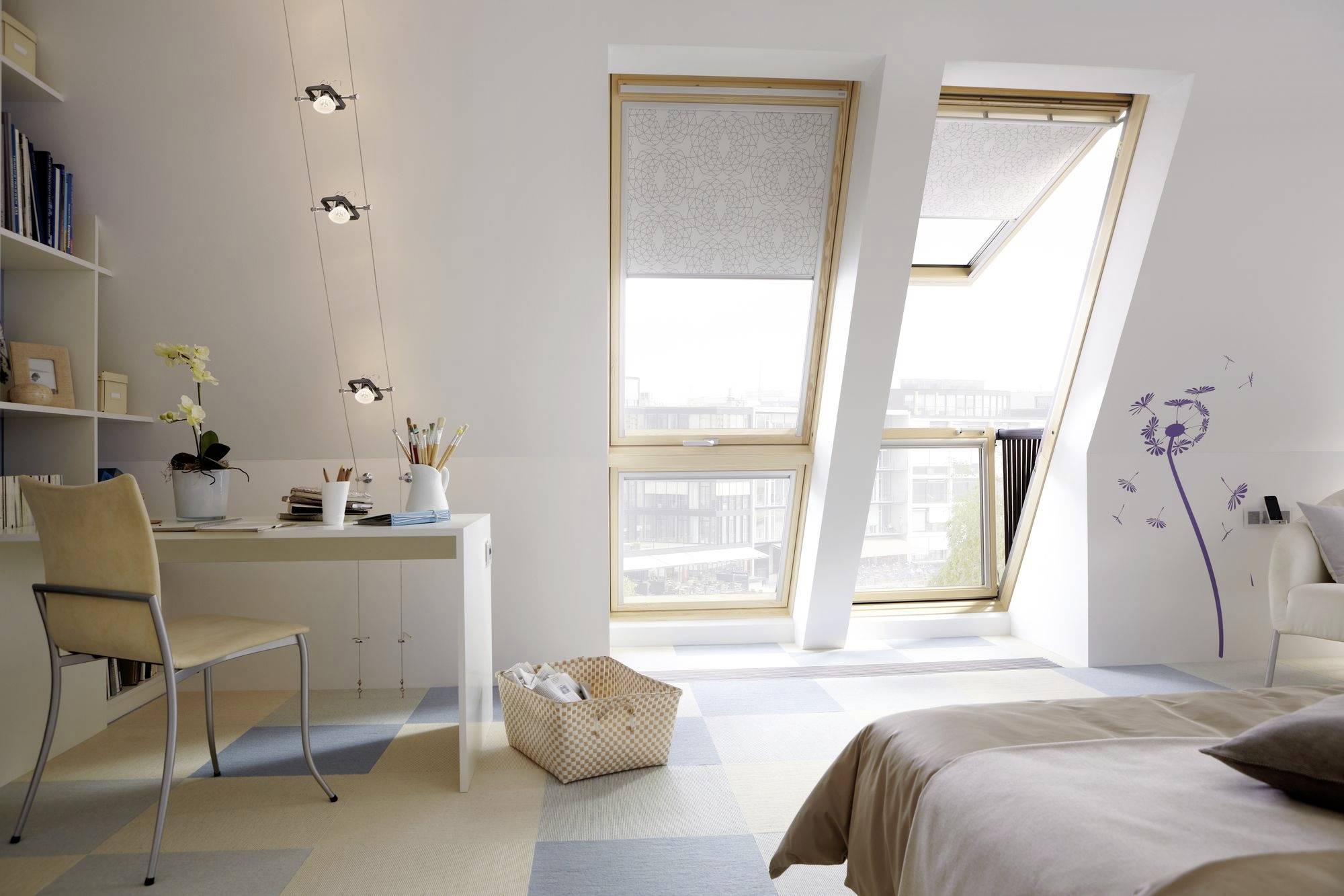 Lichte slaapkamer met dakraam, bureau met stoel, bed en planken; een mand staat op de vloer.