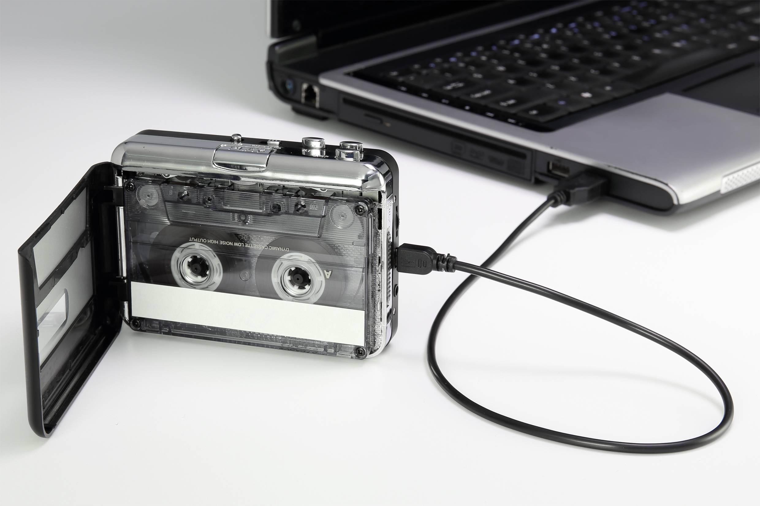 Een cassetterecorder wordt via een USB-kabel verbonden met een laptop, symboliseert de digitalisering van analoge audioformaten.