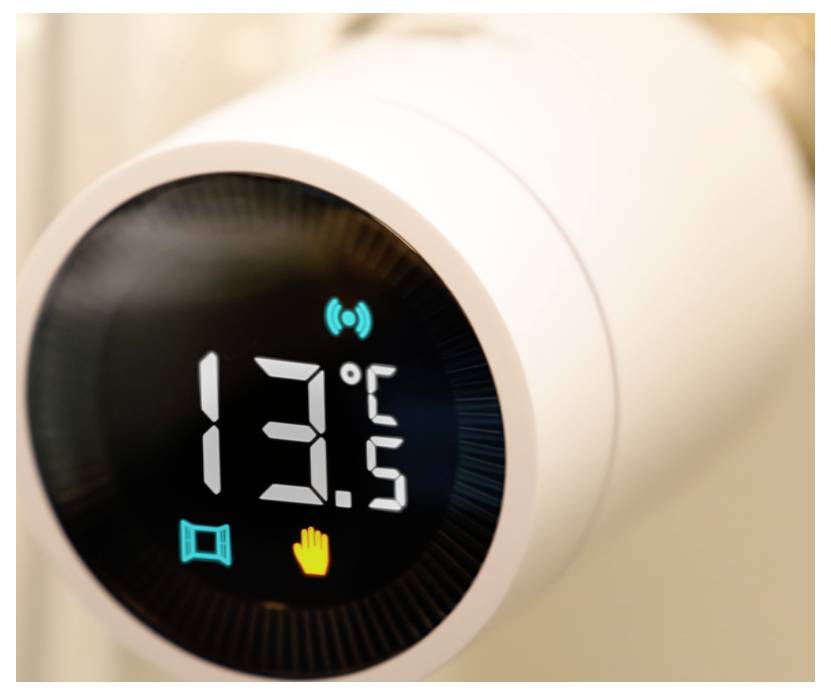 Close-up van een witte slimme thermostaat die 13,5°C weergeeft, met Wi-Fi-, raam- en handpictogrammen op een zwart scherm.