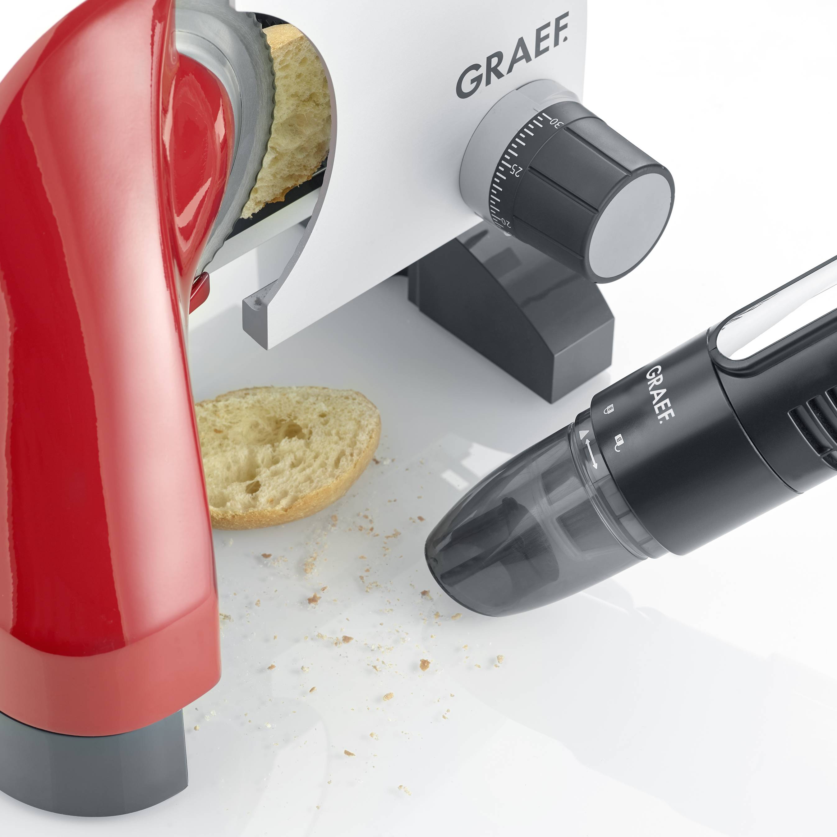 'Graef Allessnijder' snijdt brood; kruimels liggen op tafel. Rode hendel en zwarte instelknoppen zichtbaar.