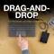 Een hand houdt een zwarte externe harde schijf naast een laptop op een bureau. Tekst op de afbeelding: 'Drag-and-Drop, voorgeformatteerd voor Windows en Mac'.