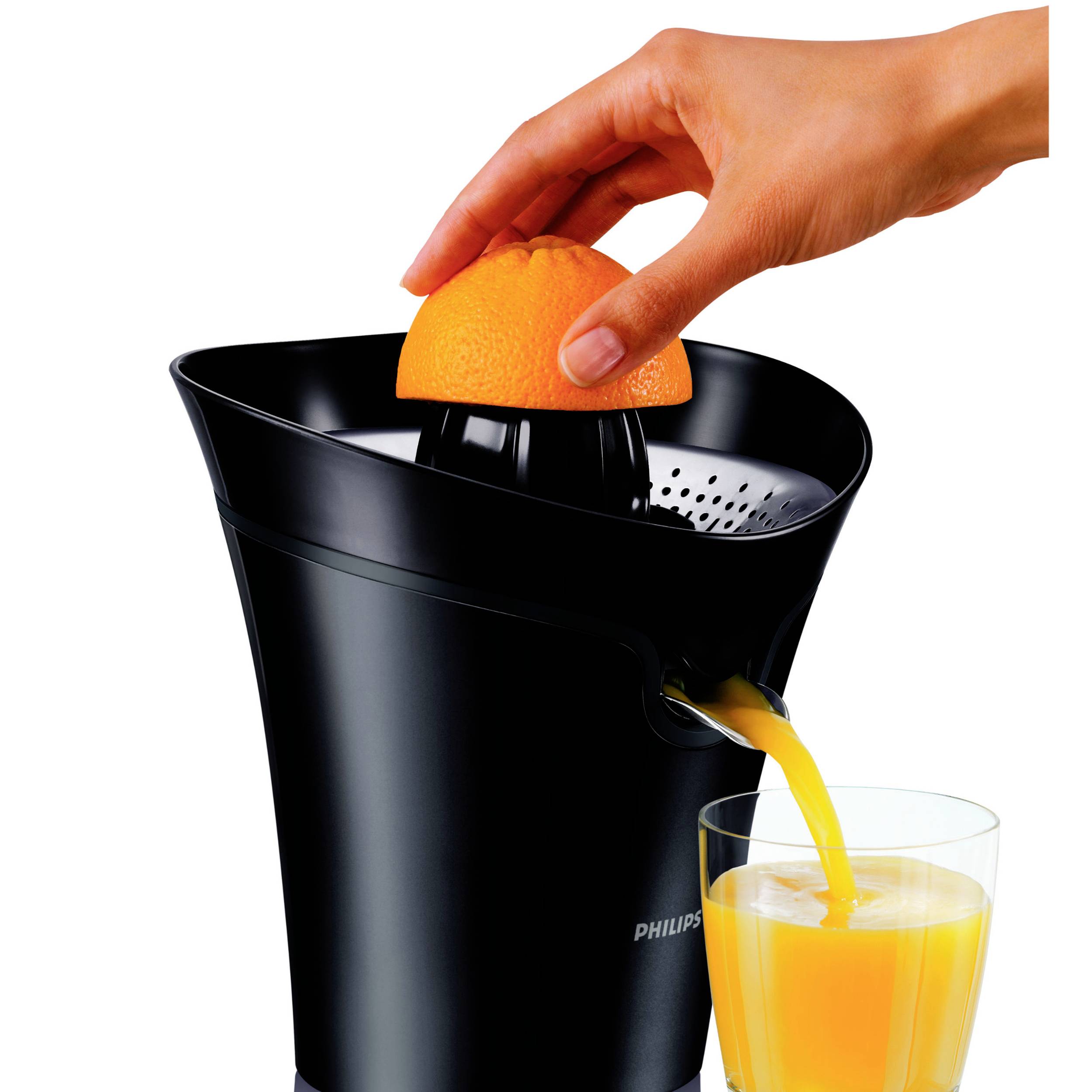 Een hand perst een sinaasappel uit op een zwarte sapcentrifuge. Daaronder stroomt verse sinaasappelsap in een glas.