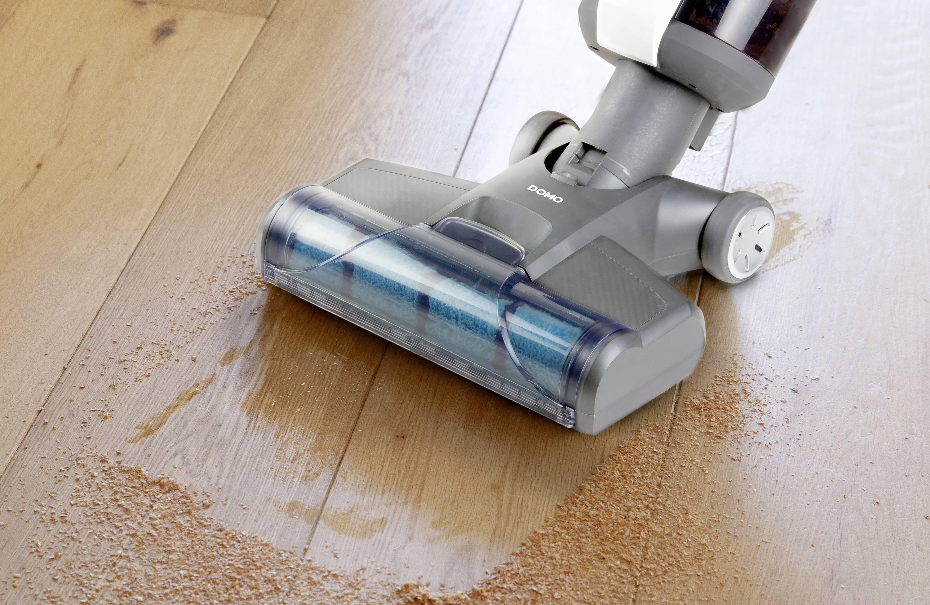 Een stofzuiger verwijdert kruimels van een houten vloer en toont zijn reinigingsprestaties.