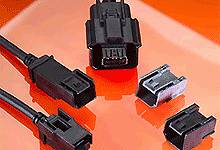 Verschillende zwarte en zilveren elektrische stekkers liggen op een oranje oppervlak.