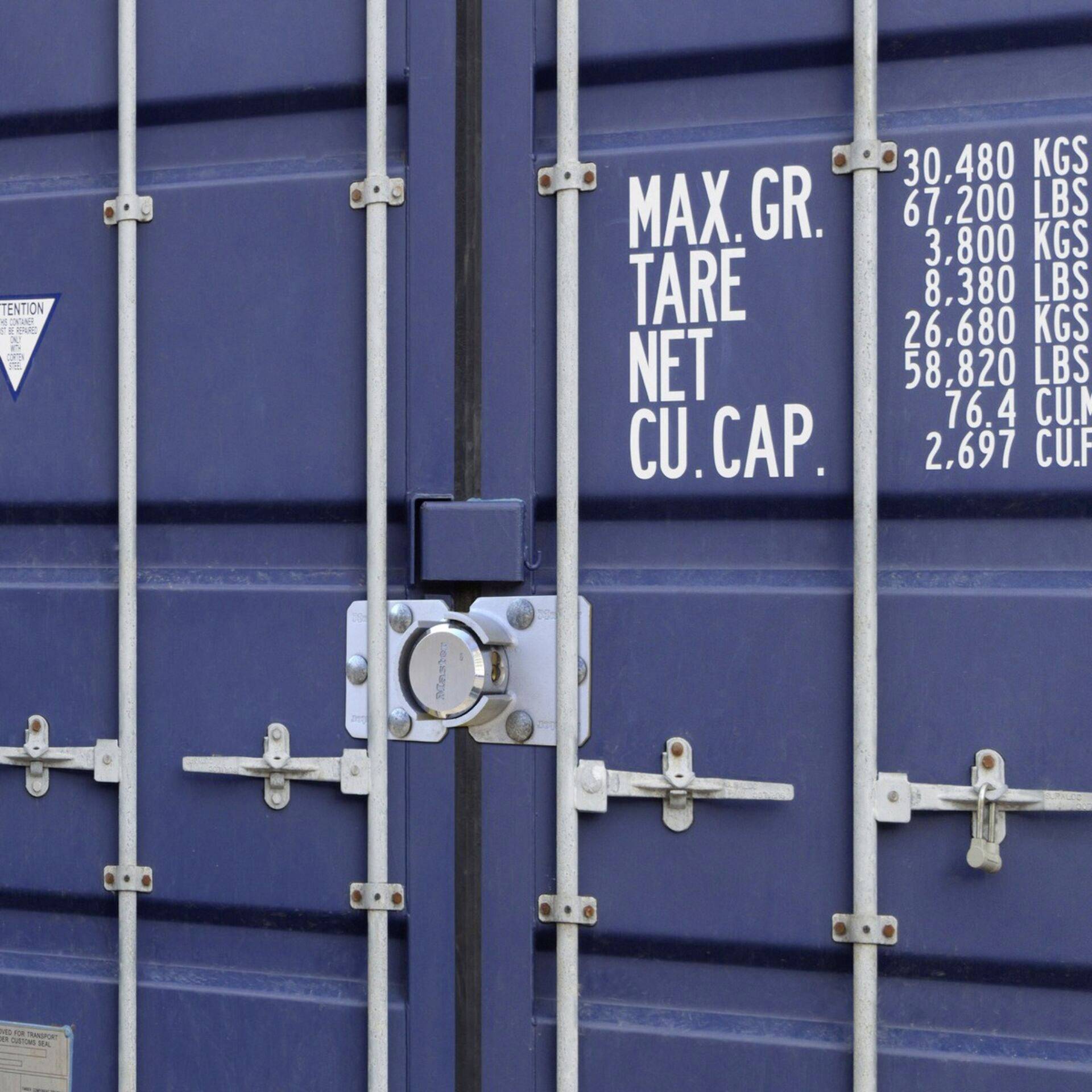 Blauwe metalen containerdeuren met vergrendeling. Opschrift toont maximale draagcapaciteit in kg en lbs, evenals volume in kubieke voet.