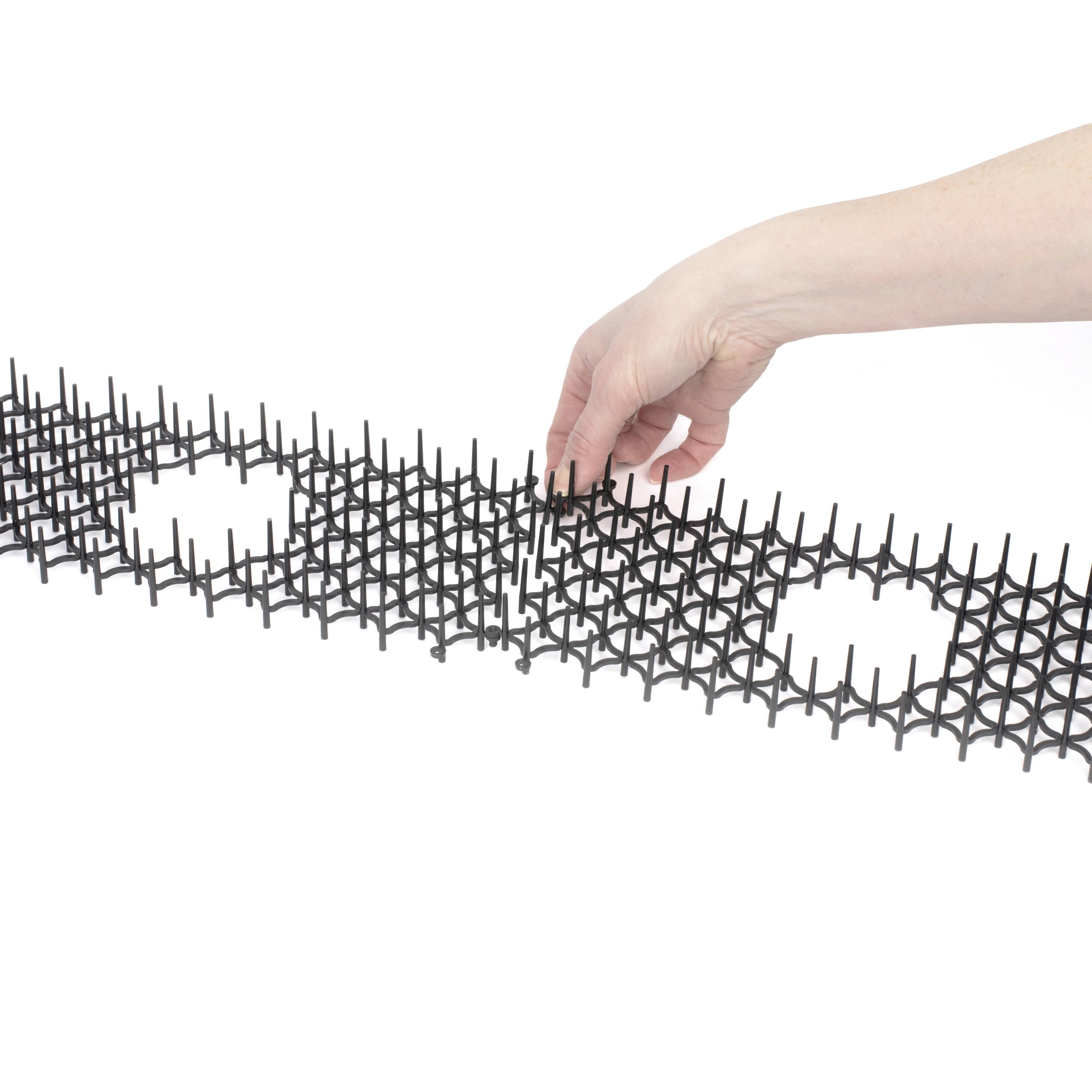 'Hand past zwarte, roosterachtige structuur met ronde openingen aan op witte achtergrond.'