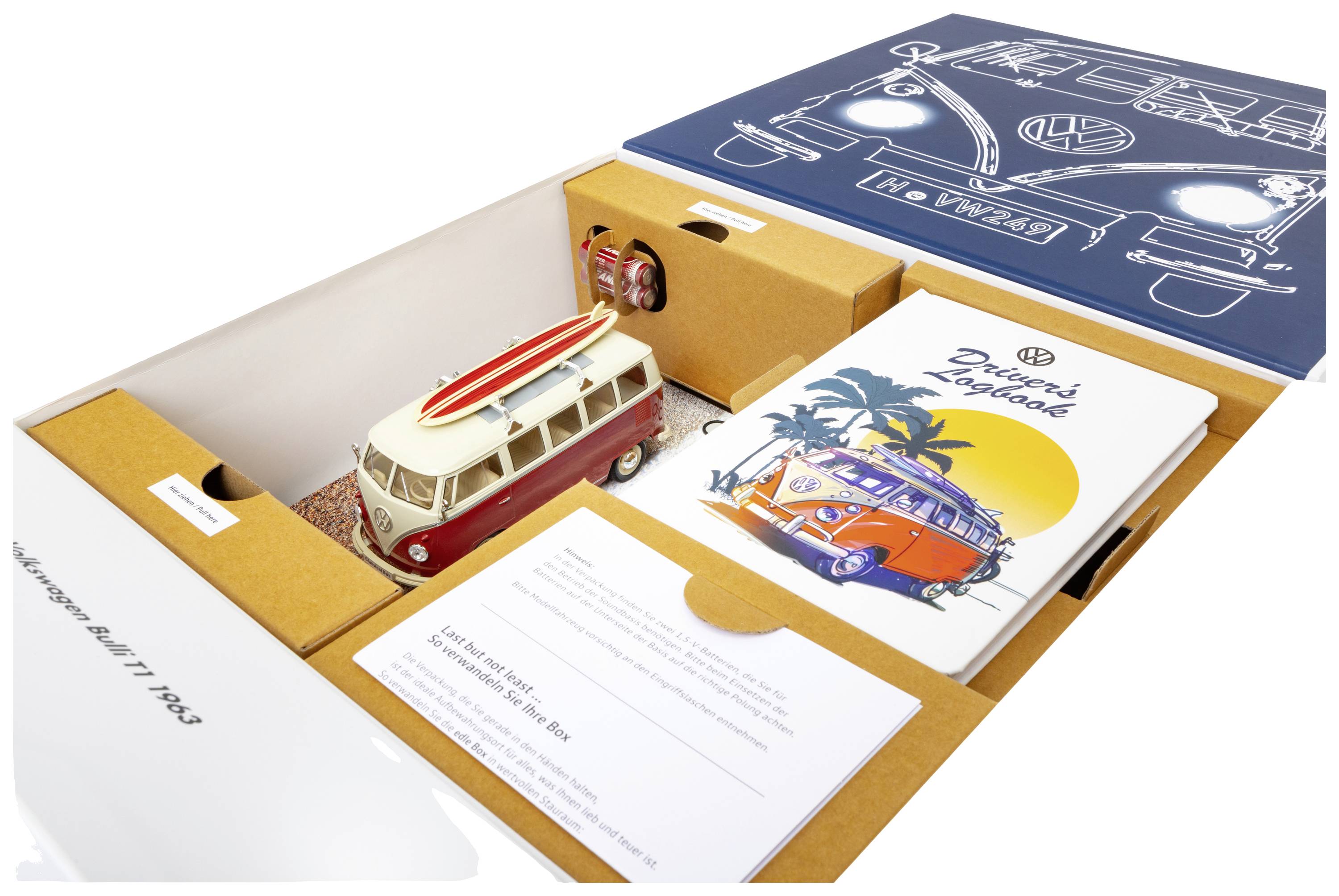 Een geopende set met een VW-busmodel, een boek 'Drivers Notebook' en andere verzamelwaardige voorwerpen.