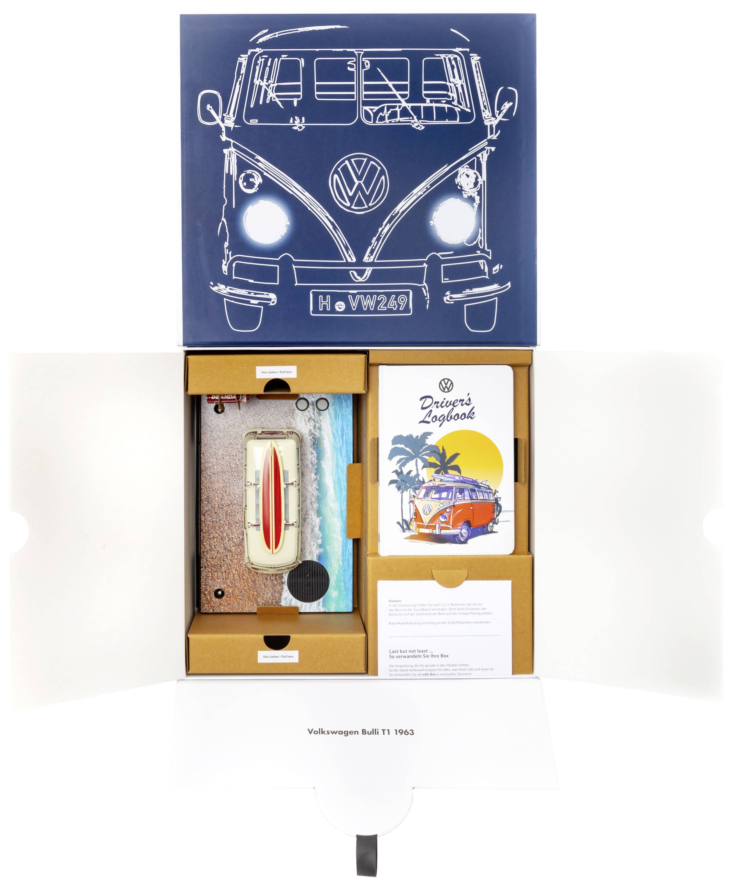 Een geopende doos toont een model van een VW Bus, een notitieboek met 'Drivers Logbook', en een ansichtkaart met een VW Bulli voor palmbomen.