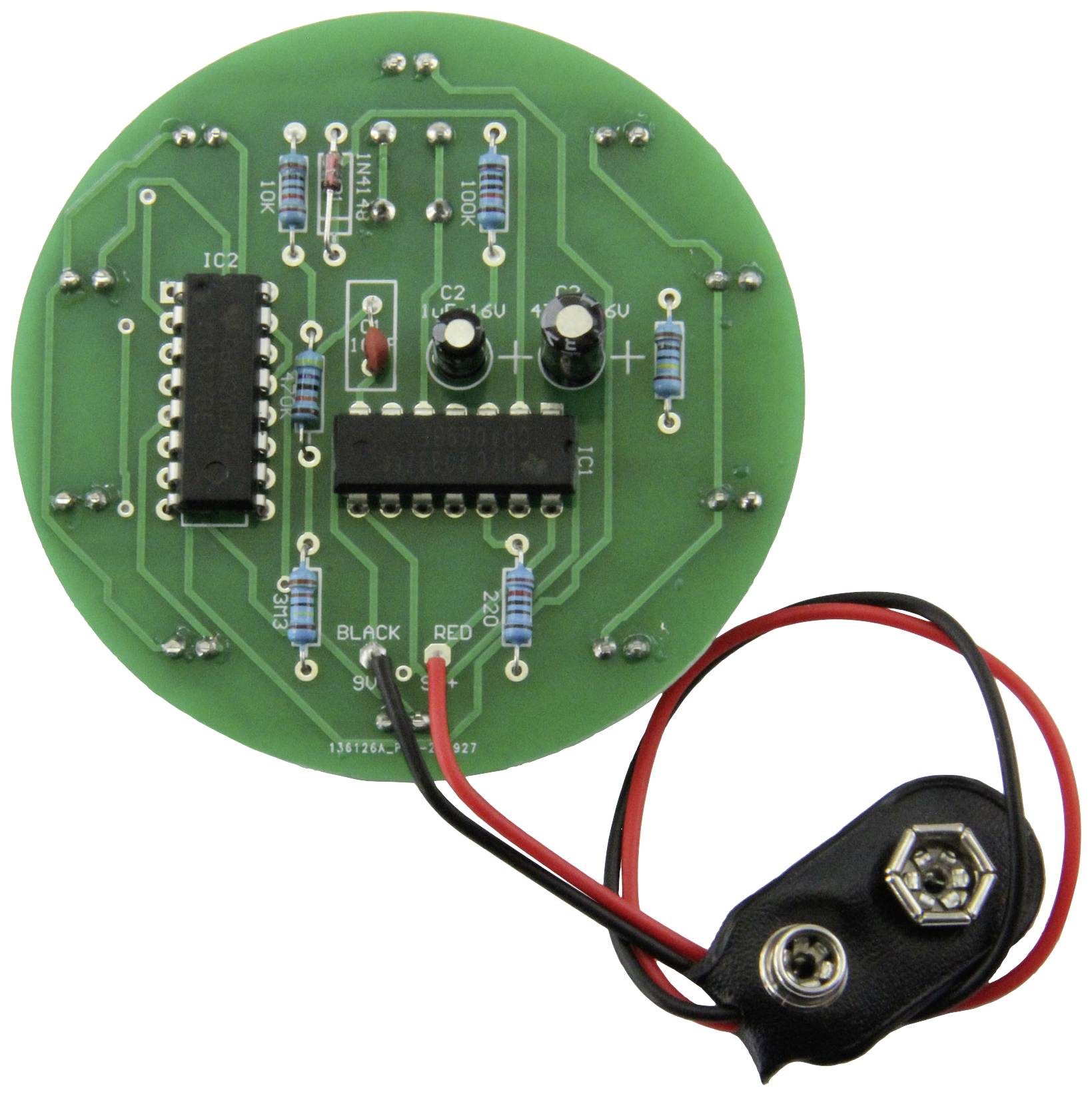 Ronde groene printplaat met verschillende elektronische componenten zoals weerstanden en chips, verbonden met een batterijclip.