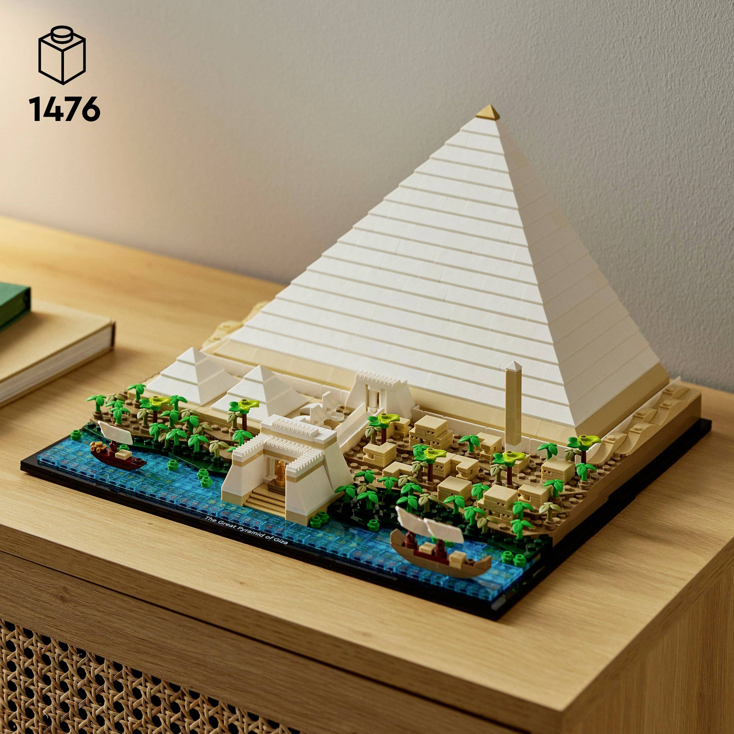 Nabootsing van een piramide gemaakt van bouwstenen, omringd door miniatuurbomen en boten op een tafel.
