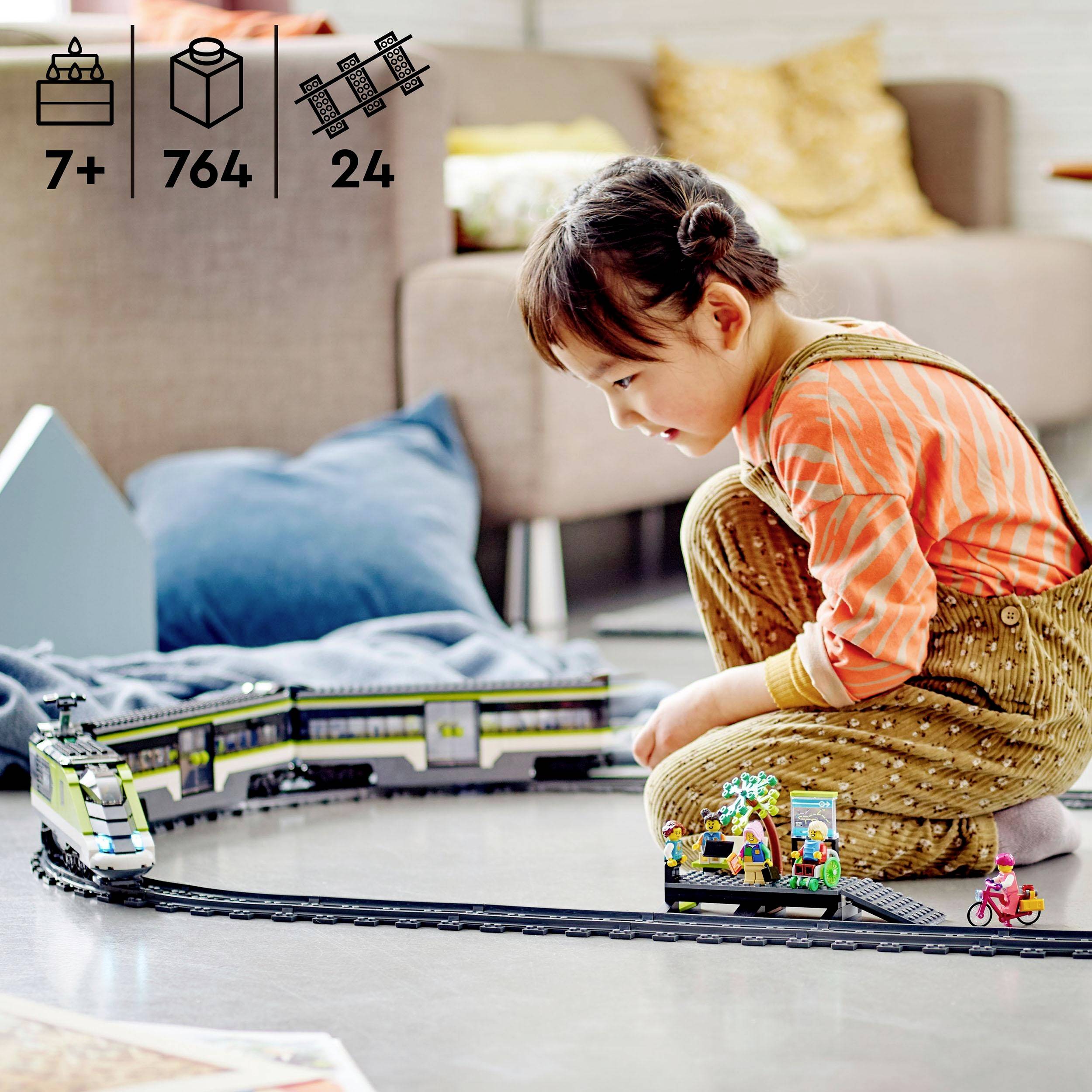 Kind speelt in de woonkamer met een speelgoedtrein op de vloer. Op de achtergrond zijn een bank en kleurrijke kussens te zien.