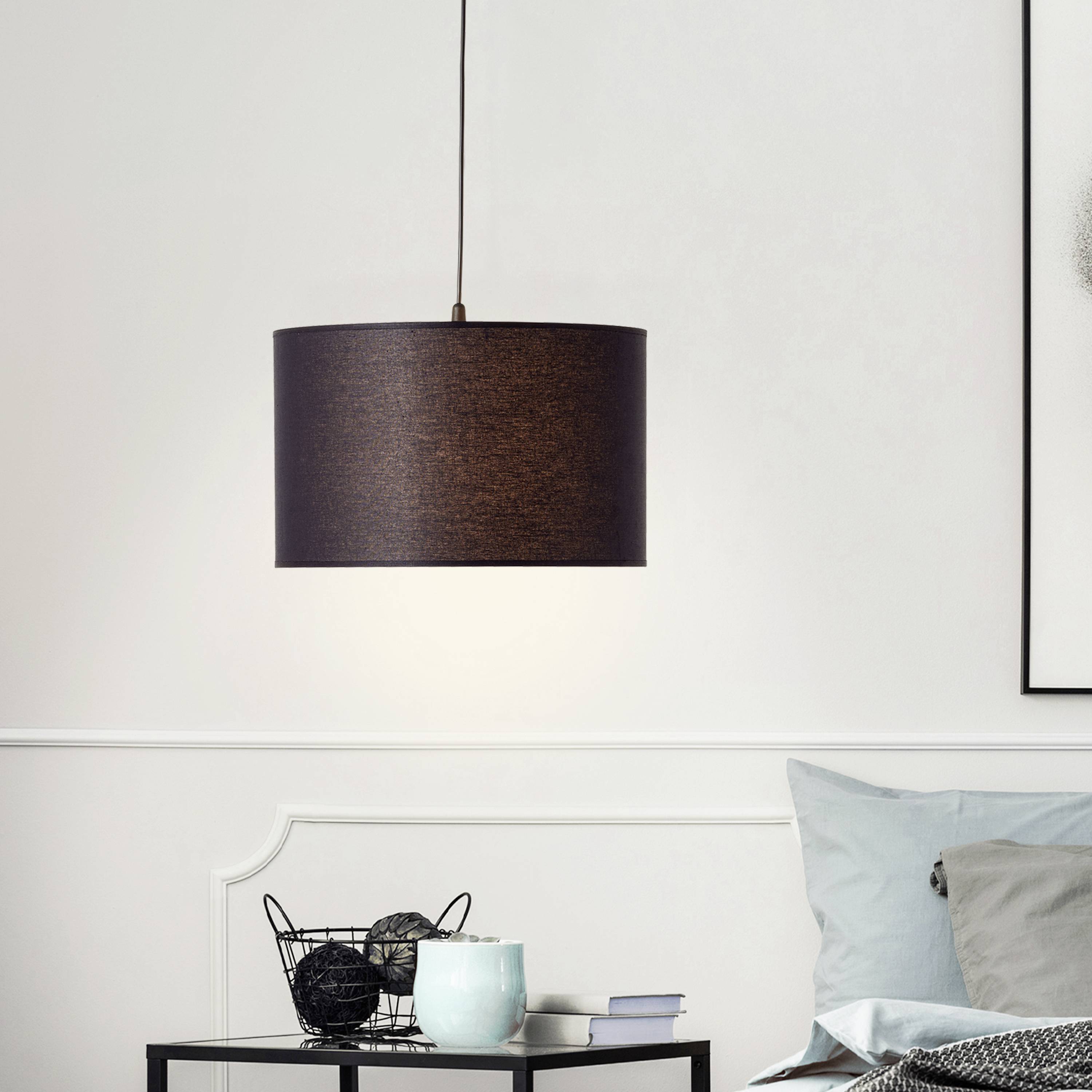 Een moderne hanglamp schijnt boven een tafel met decoraties en een bank op de achtergrond.