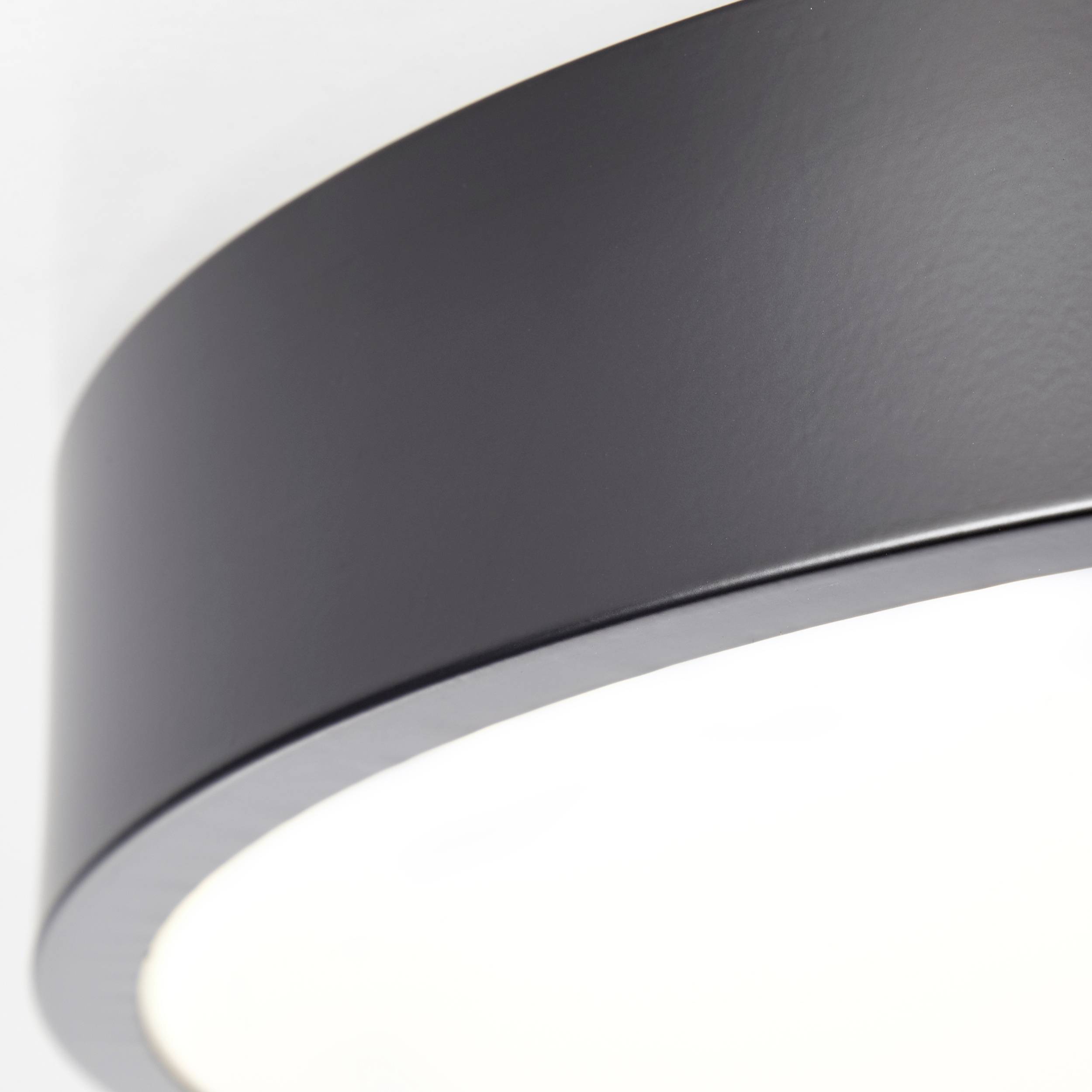 Een ronde, zwarte plafondlamp met warm, diffuus licht. Ideaal voor moderne interieurs.