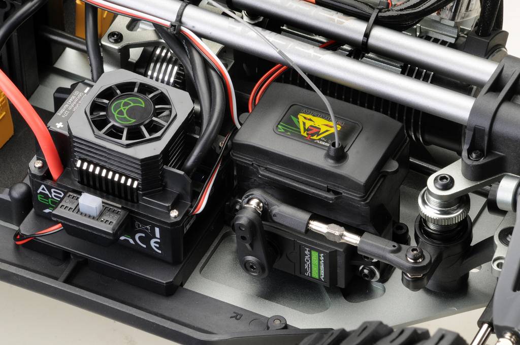 Close-up van het interieur van een modelauto met een servomotor en koelventilator. Kabels zijn aangesloten, technische details zijn zichtbaar.