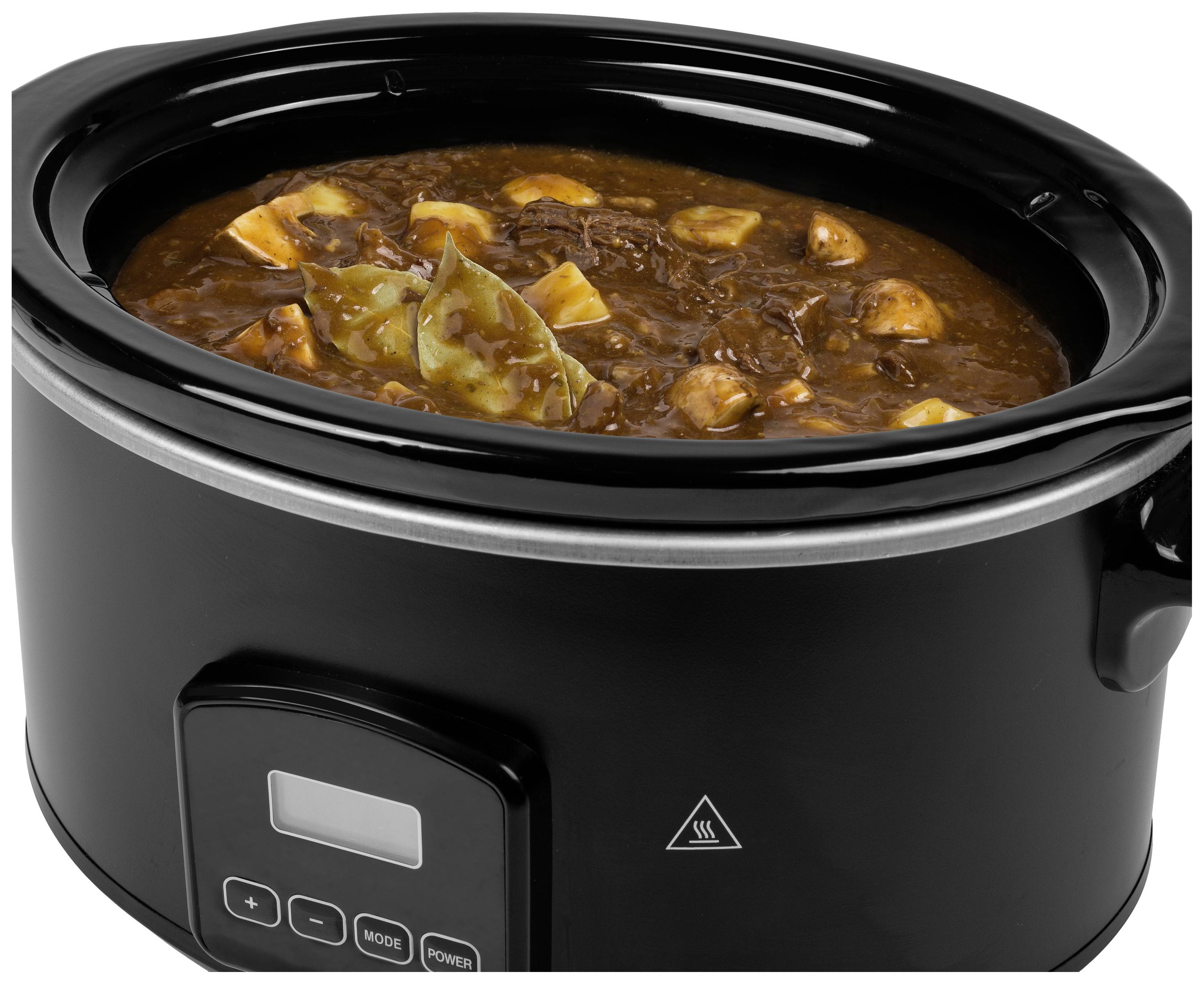 Een zwarte slowcooker gevuld met stoofpot. De stoofpot bevat stukjes vlees, aardappelen en laurierblaadjes, zichtbaar in bruine saus.