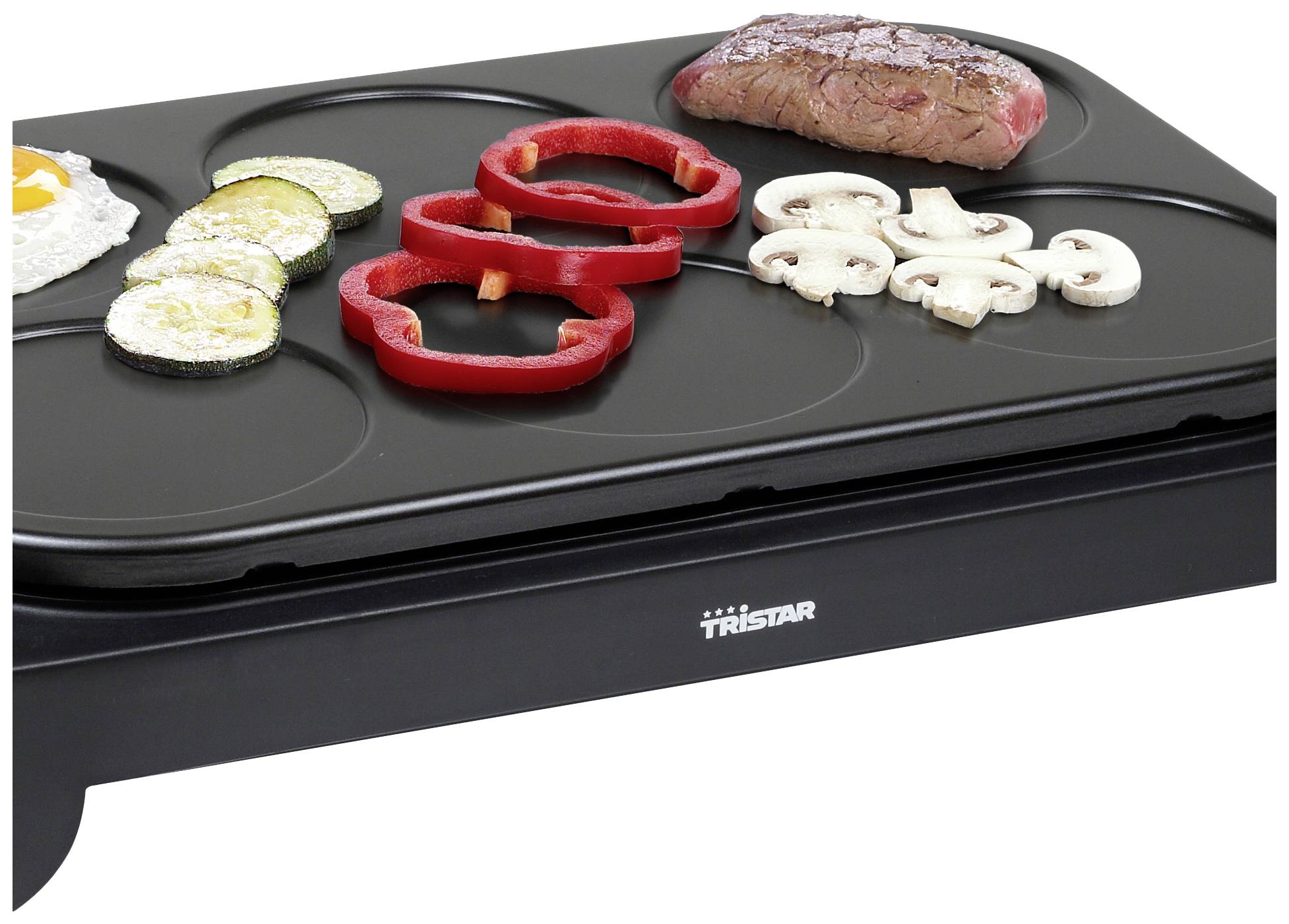 Een grill met courgetteplakjes, paprikaringen, champignons, een biefstuk en een spiegelei. Ideaal voor het gelijktijdig braden van verschillende ingrediënten.