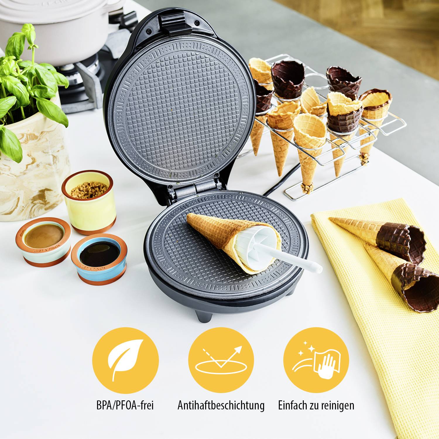 Wafelijzer op keukentafel met gebakken croissant en kommen. Afgebeeld zijn symbolen: BPA/PFOA-vrij, anti-aanbak, gemakkelijk te reinigen.