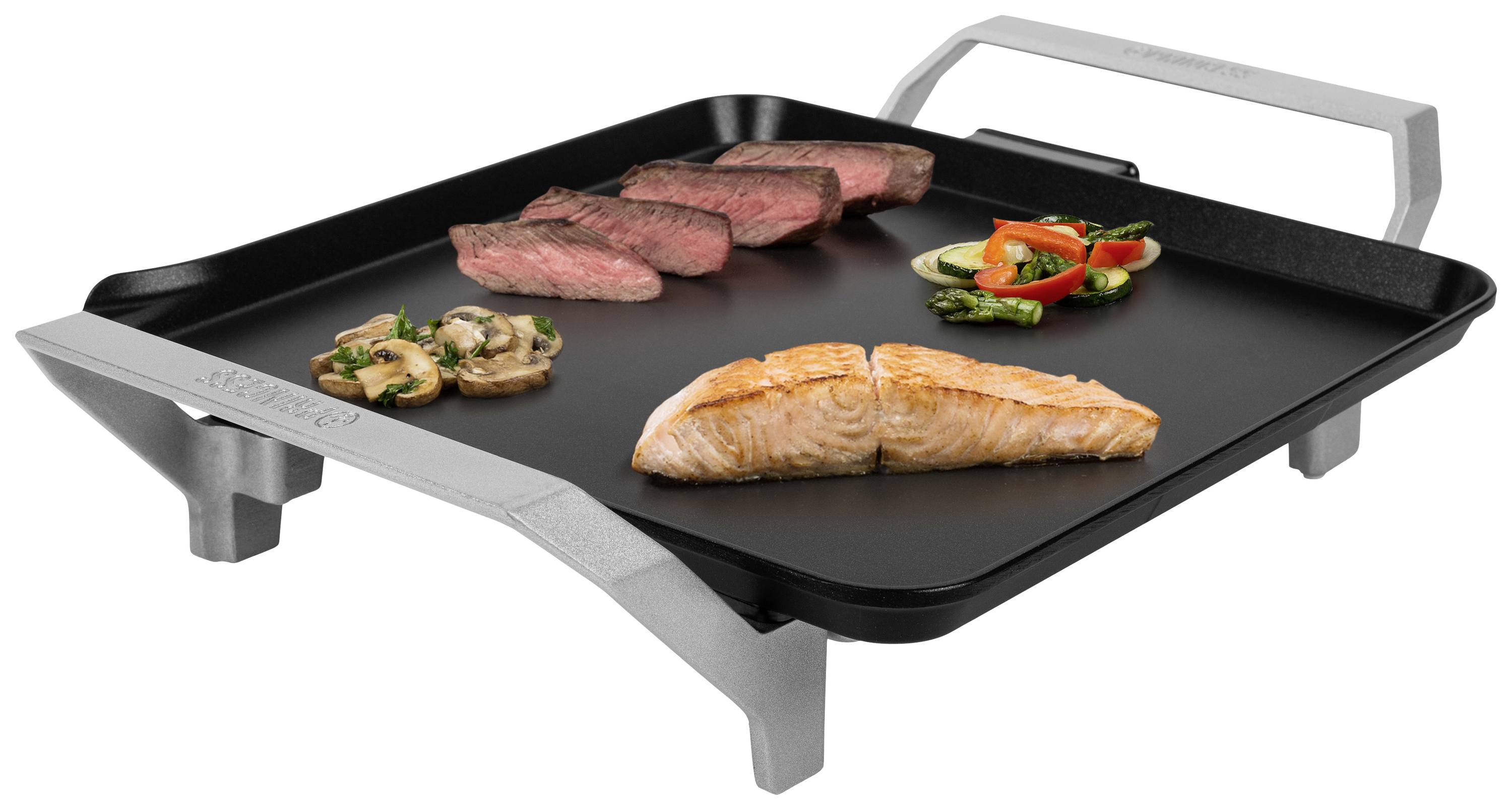 Grillplaat met gegrilde zalm, steak, champignons en groenten, vierkant en verhit, met handvatten aan de zijkanten.
