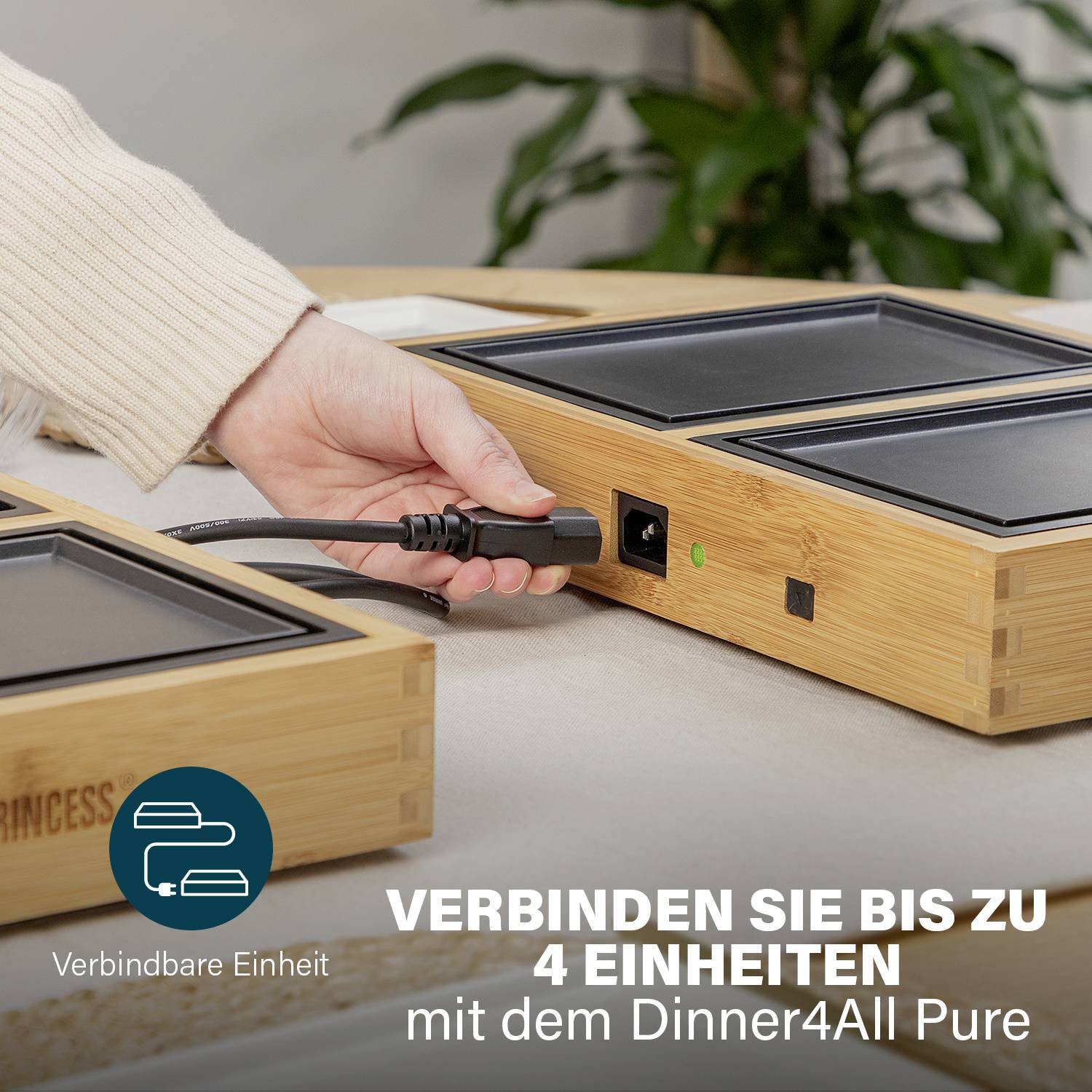 Een persoon verbindt twee compacte, vierkante, houten apparaten via een kabel. Tekst op de afbeelding: 'Verbind tot 4 eenheden'.