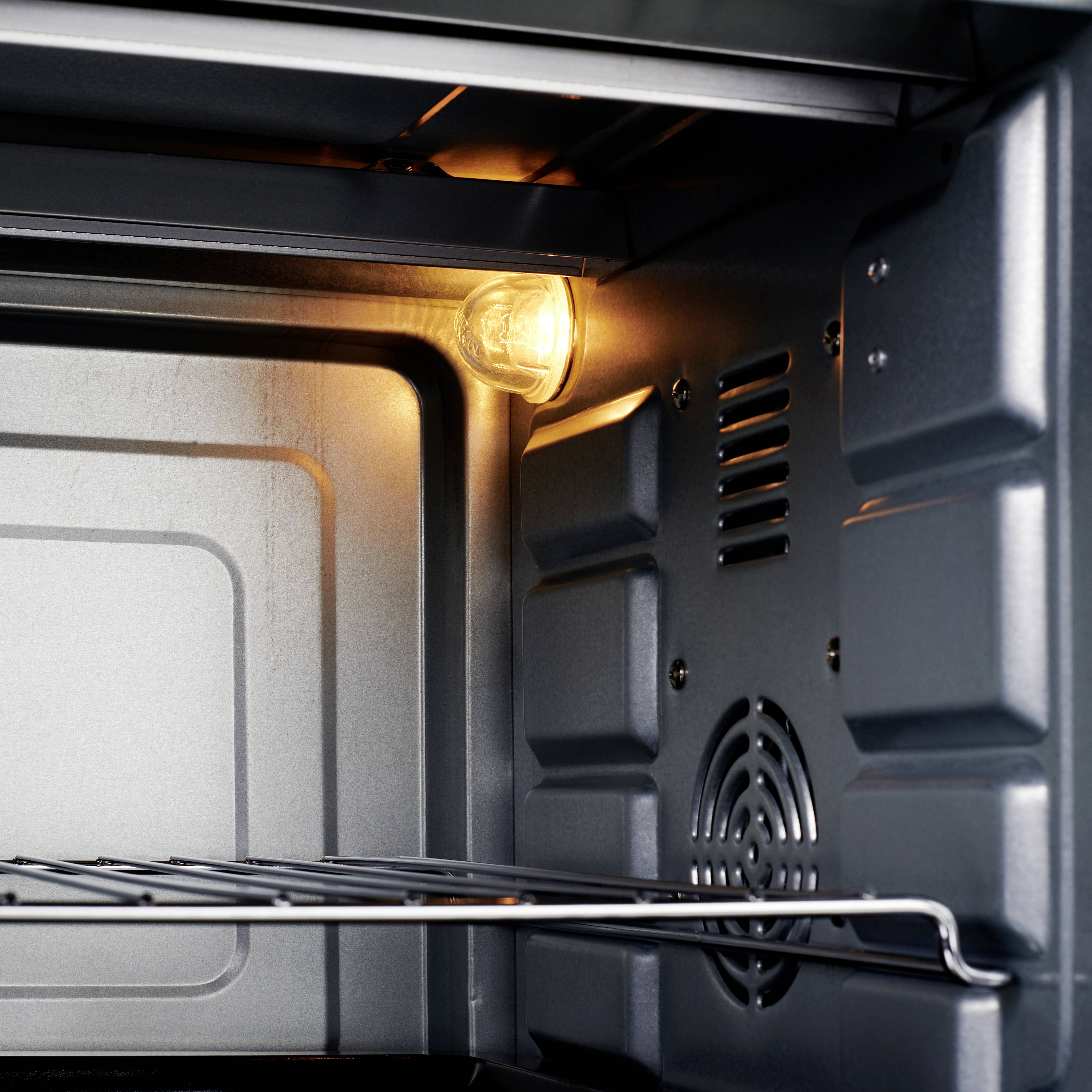 Een open oven met een rooster, verlicht door een binnenverlichting.