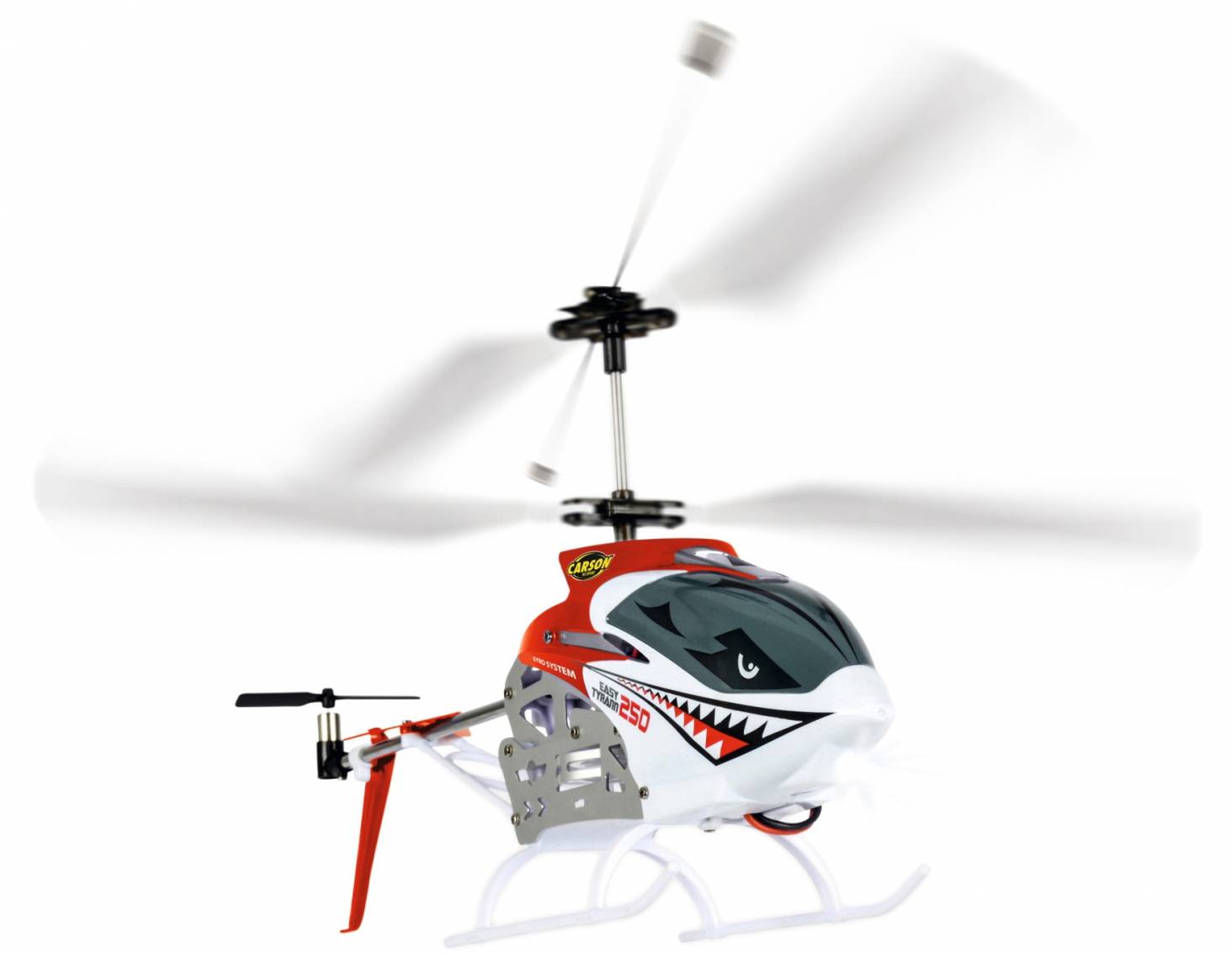 Een modelhelikopter met een rood-wit ontwerp en een haaienmuil-opdruk vliegt met draaiende rotorbladen.